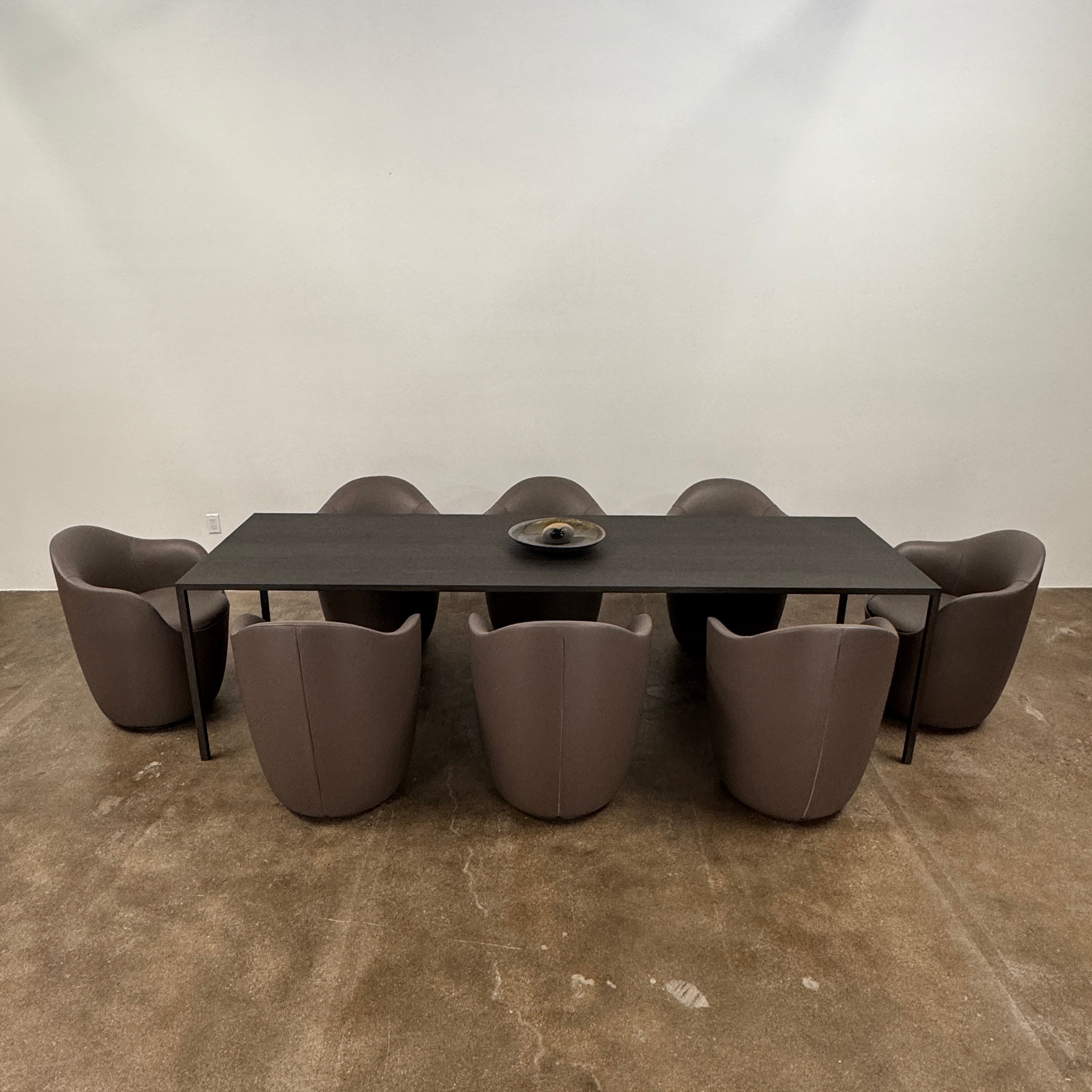 Two modern brown DWR Lina Swivel Dining Chairs with rounded backs and smooth upholstery, placed side by side on a white background.