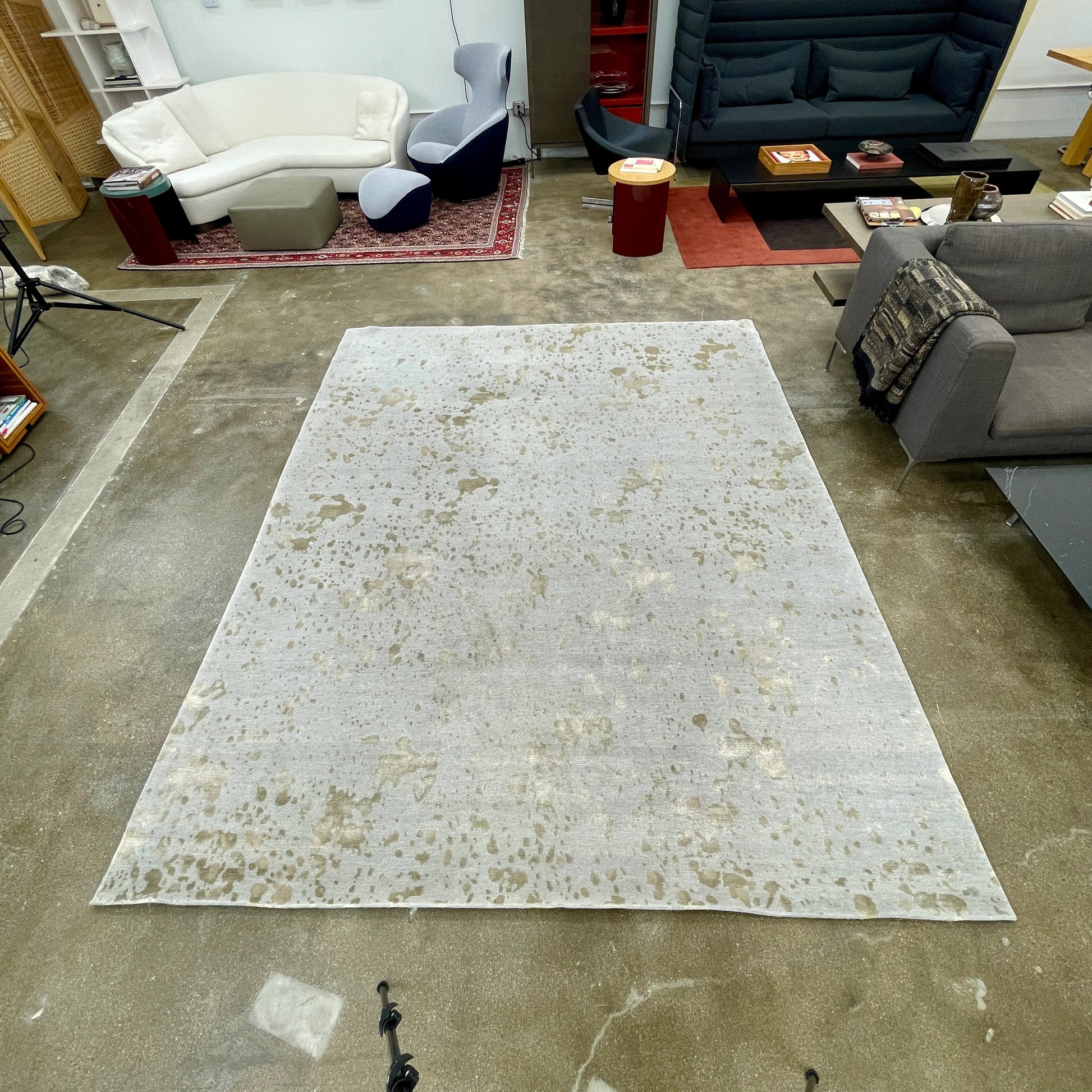 A section of the Delinear's 8 x 10 Delinier Splatter Rug features an abstract design with beige and gray spots, enhanced by Swiss Chromium Dye on Himalayan wool for vibrant detail.