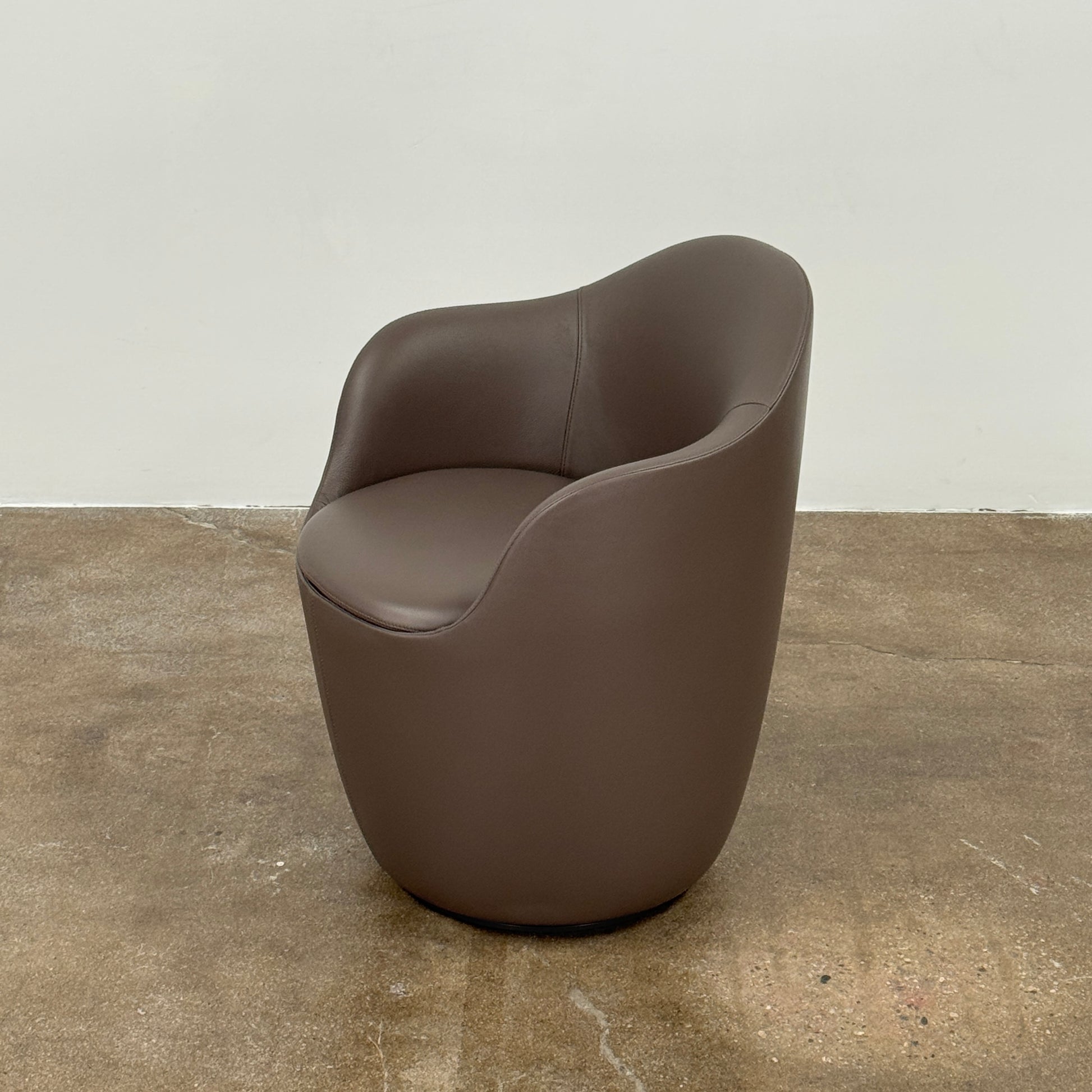 Two modern brown DWR Lina Swivel Dining Chairs with rounded backs and smooth upholstery, placed side by side on a white background.