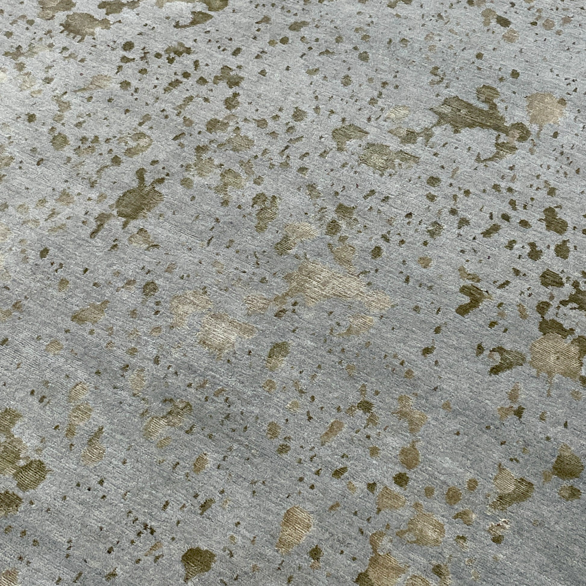 A section of the Delinear's 8 x 10 Delinier Splatter Rug features an abstract design with beige and gray spots, enhanced by Swiss Chromium Dye on Himalayan wool for vibrant detail.