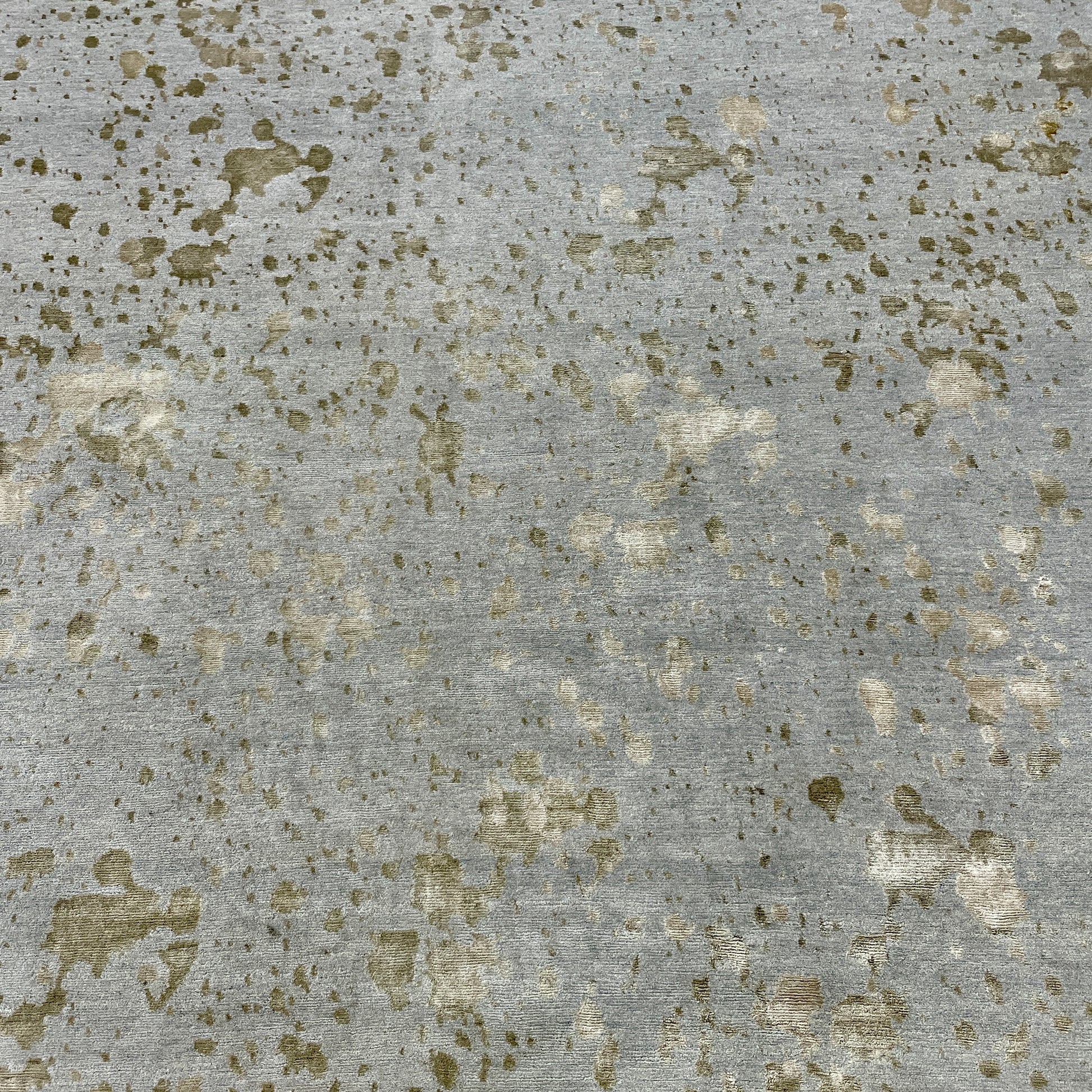 A section of the Delinear's 8 x 10 Delinier Splatter Rug features an abstract design with beige and gray spots, enhanced by Swiss Chromium Dye on Himalayan wool for vibrant detail.