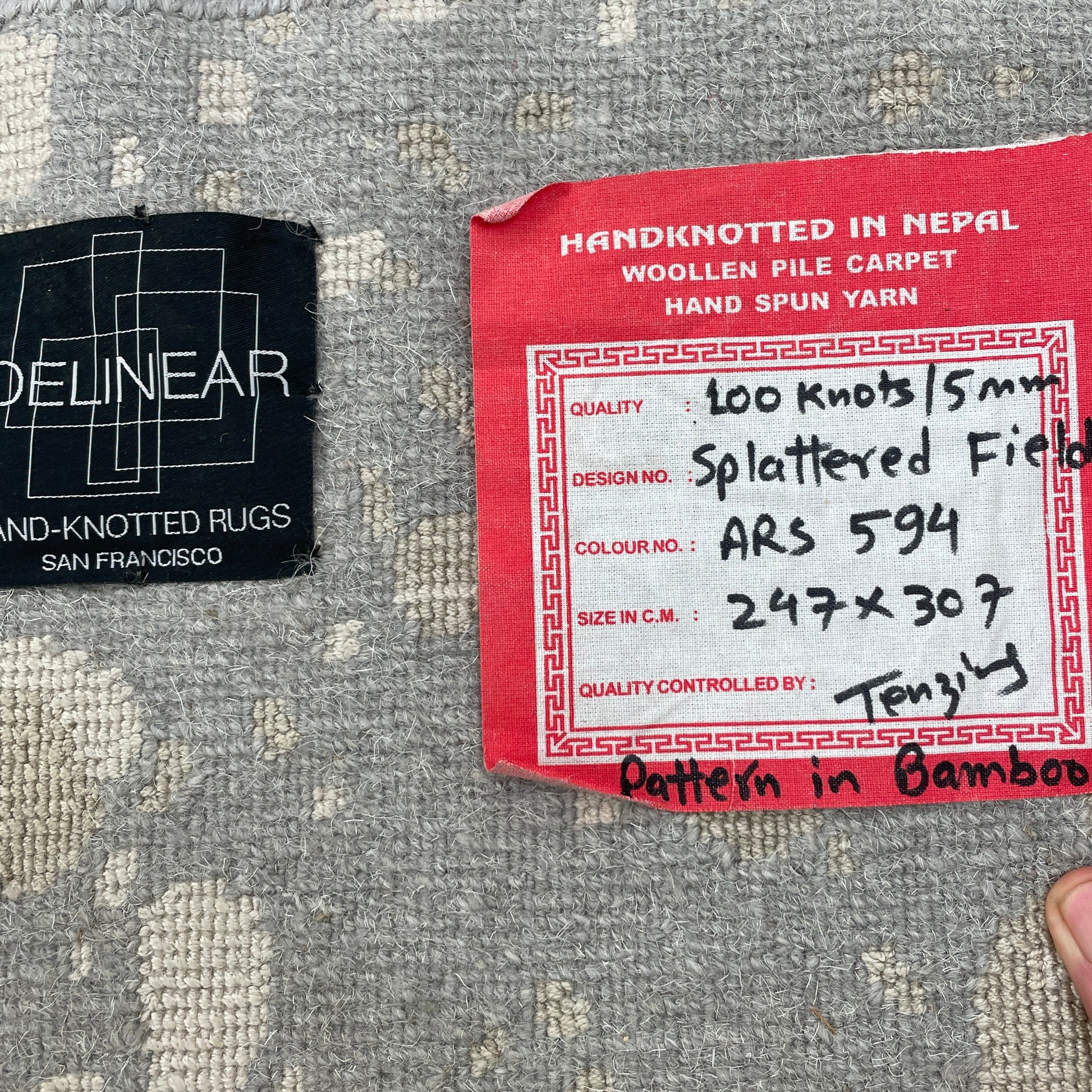 A section of the Delinear's 8 x 10 Delinier Splatter Rug features an abstract design with beige and gray spots, enhanced by Swiss Chromium Dye on Himalayan wool for vibrant detail.