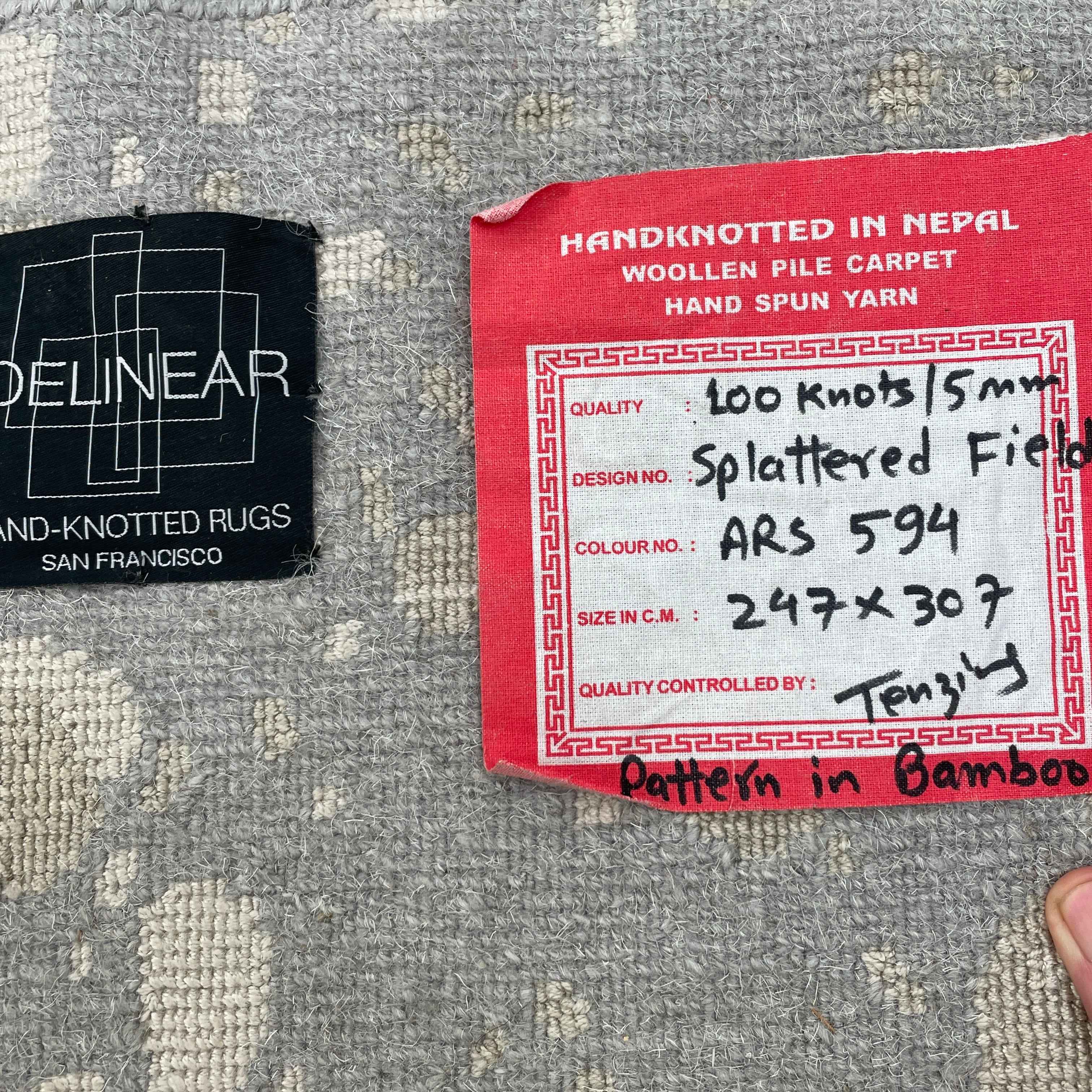 A section of the Delinear's 8 x 10 Delinier Splatter Rug features an abstract design with beige and gray spots, enhanced by Swiss Chromium Dye on Himalayan wool for vibrant detail.