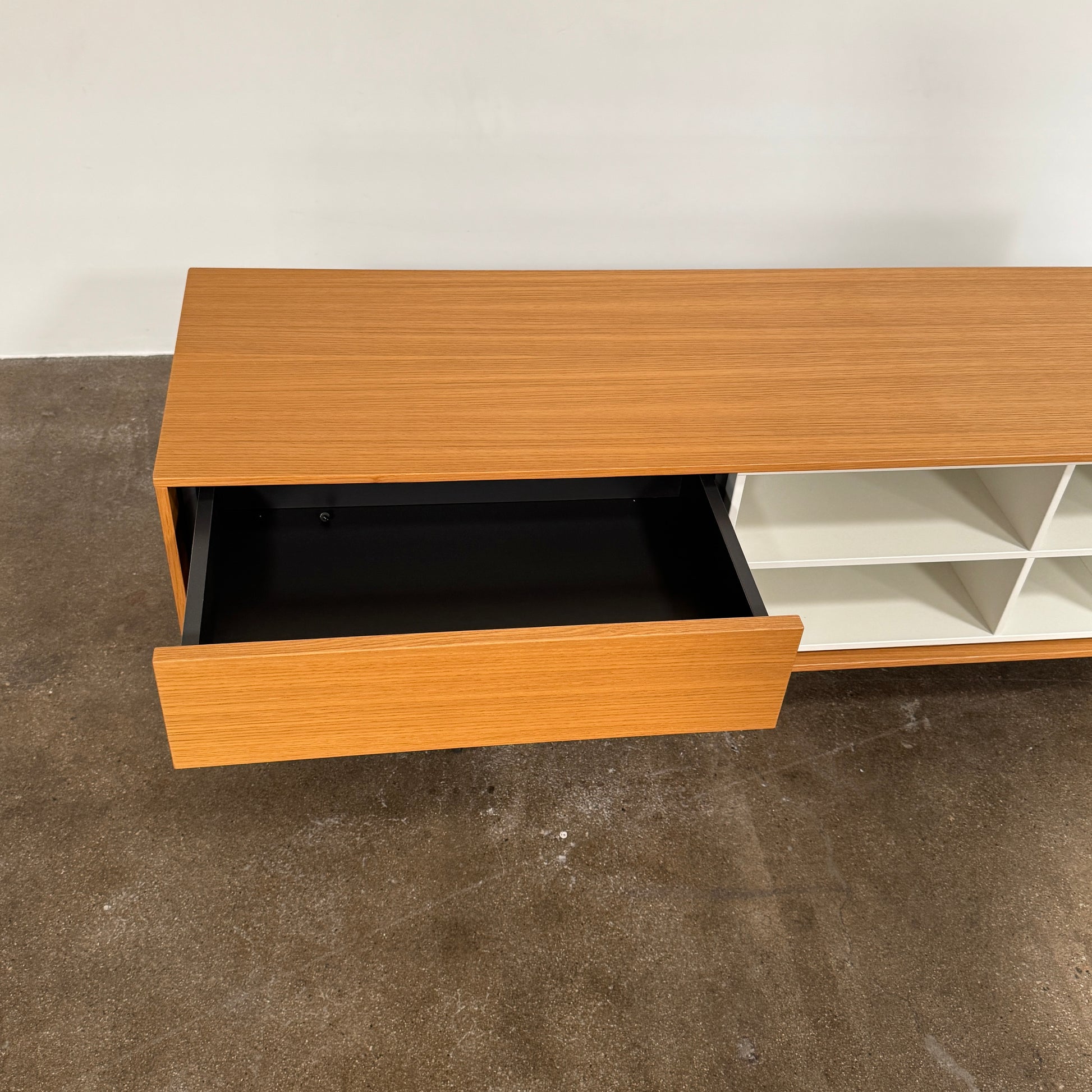 The Treku Aura Media Console by Treku features black metal legs, three left drawers, four open white center shelves, and a right white cabinet door—ideal for minimalist design and organizing your media equipment.