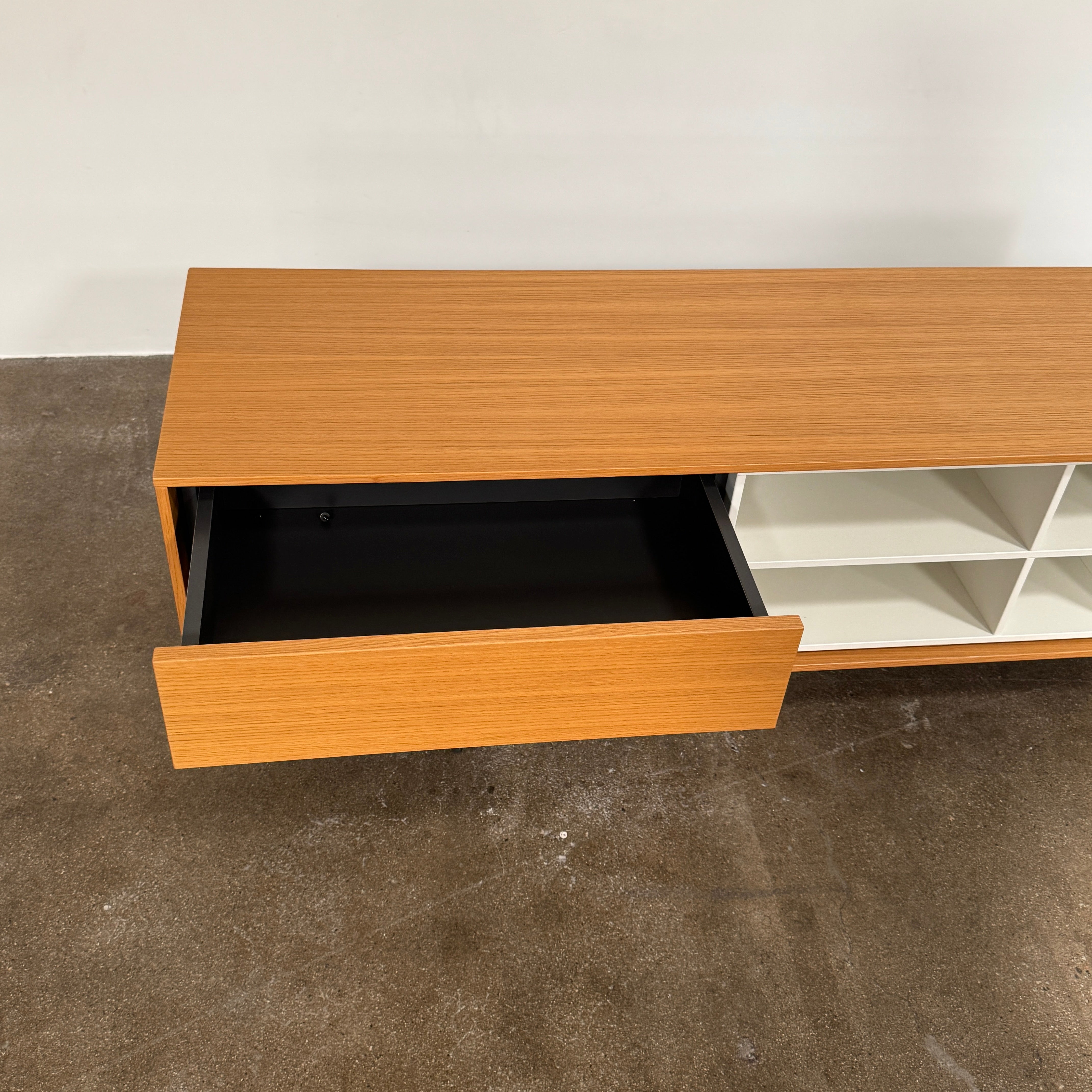 The Treku Aura Media Console by Treku features black metal legs, three left drawers, four open white center shelves, and a right white cabinet door—ideal for minimalist design and organizing your media equipment.