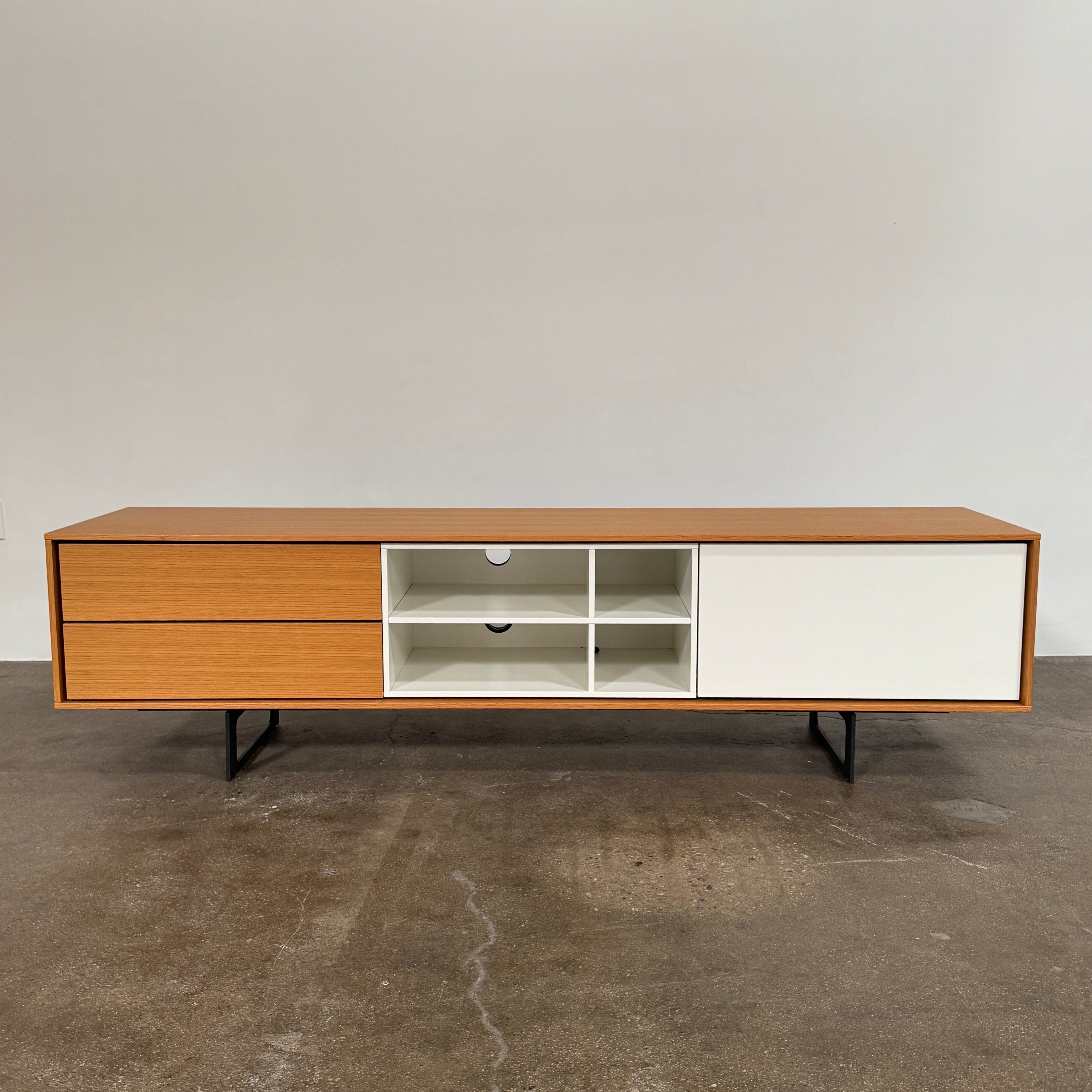 The Treku Aura Media Console by Treku features black metal legs, three left drawers, four open white center shelves, and a right white cabinet door—ideal for minimalist design and organizing your media equipment.