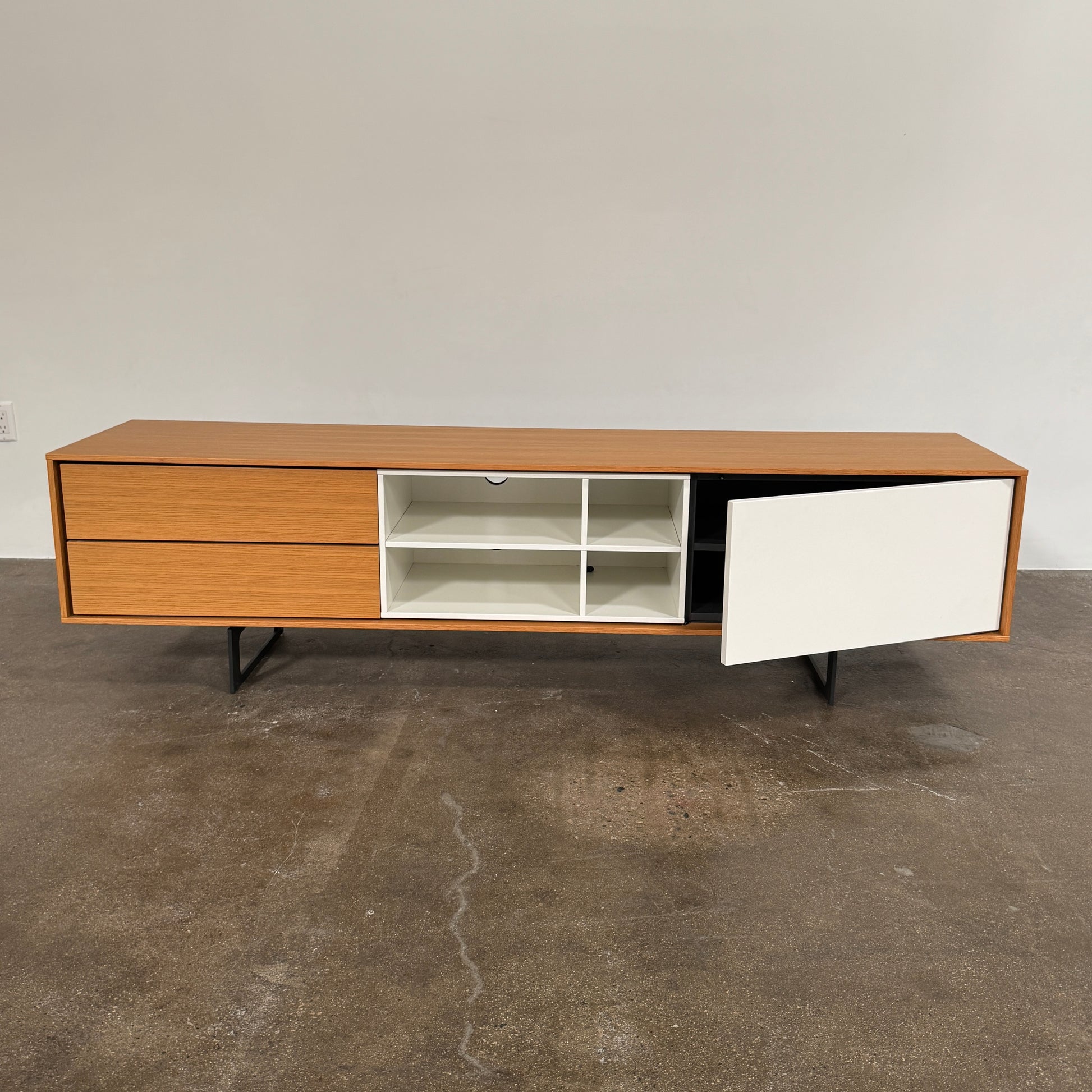 The Treku Aura Media Console by Treku features black metal legs, three left drawers, four open white center shelves, and a right white cabinet door—ideal for minimalist design and organizing your media equipment.