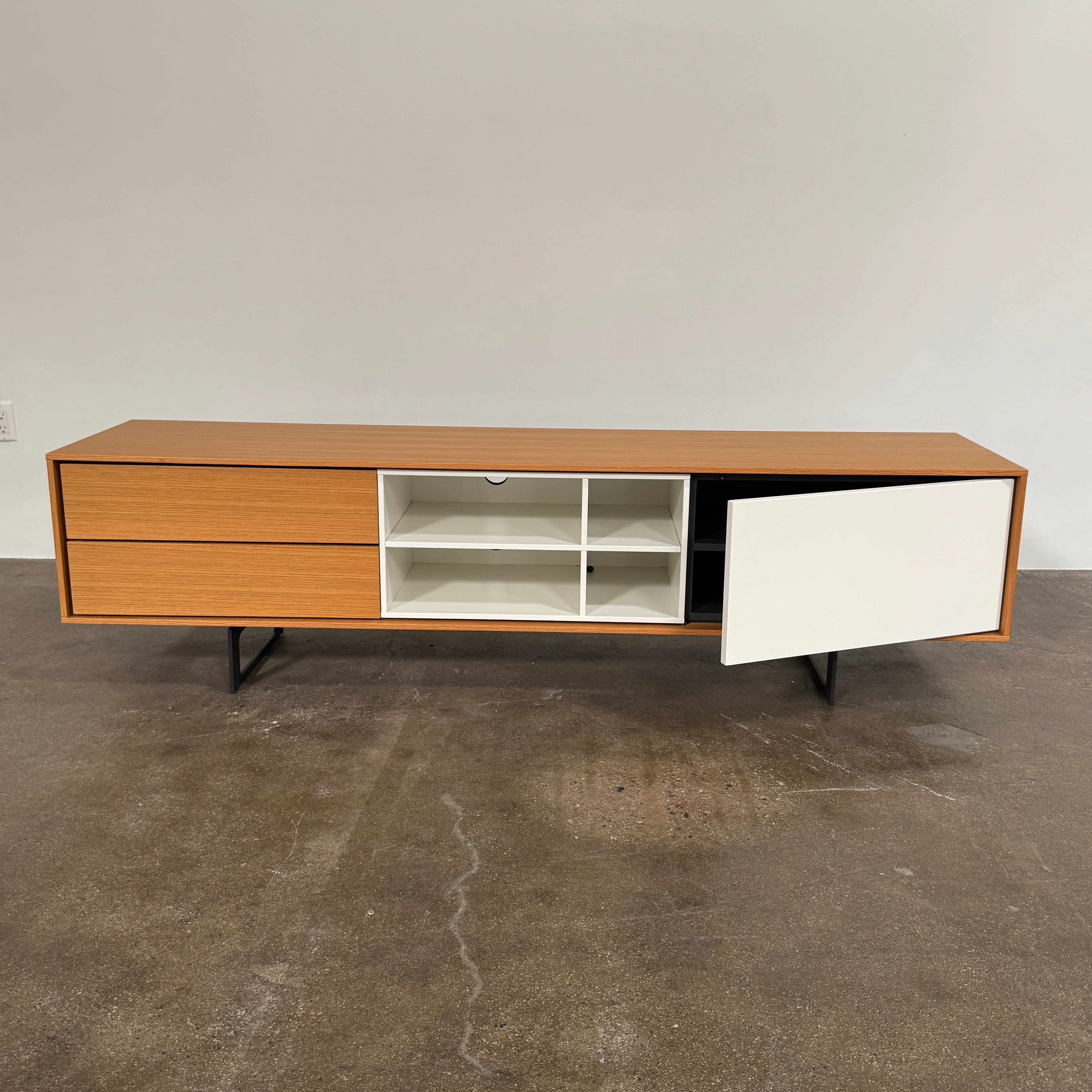 The Treku Aura Media Console by Treku features black metal legs, three left drawers, four open white center shelves, and a right white cabinet door—ideal for minimalist design and organizing your media equipment.