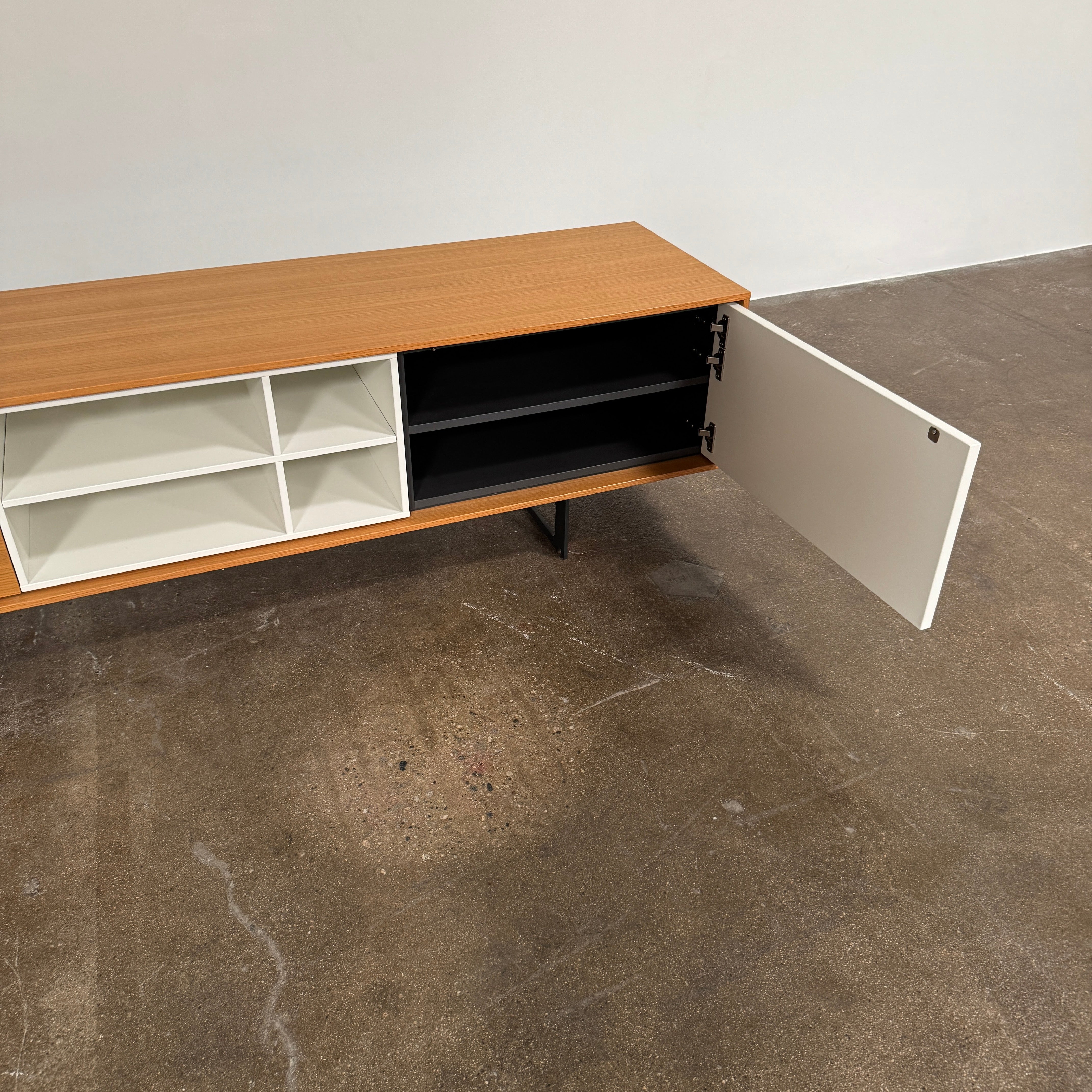 The Treku Aura Media Console by Treku features black metal legs, three left drawers, four open white center shelves, and a right white cabinet door—ideal for minimalist design and organizing your media equipment.