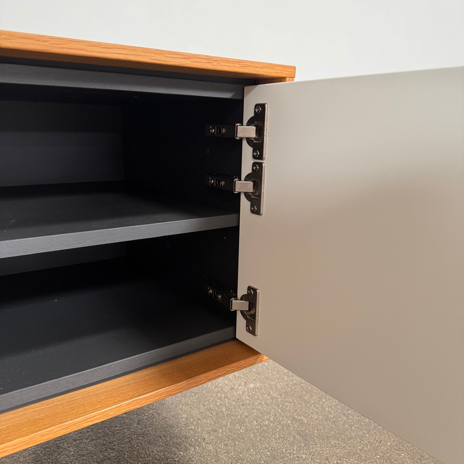 The Treku Aura Media Console by Treku features black metal legs, three left drawers, four open white center shelves, and a right white cabinet door—ideal for minimalist design and organizing your media equipment.