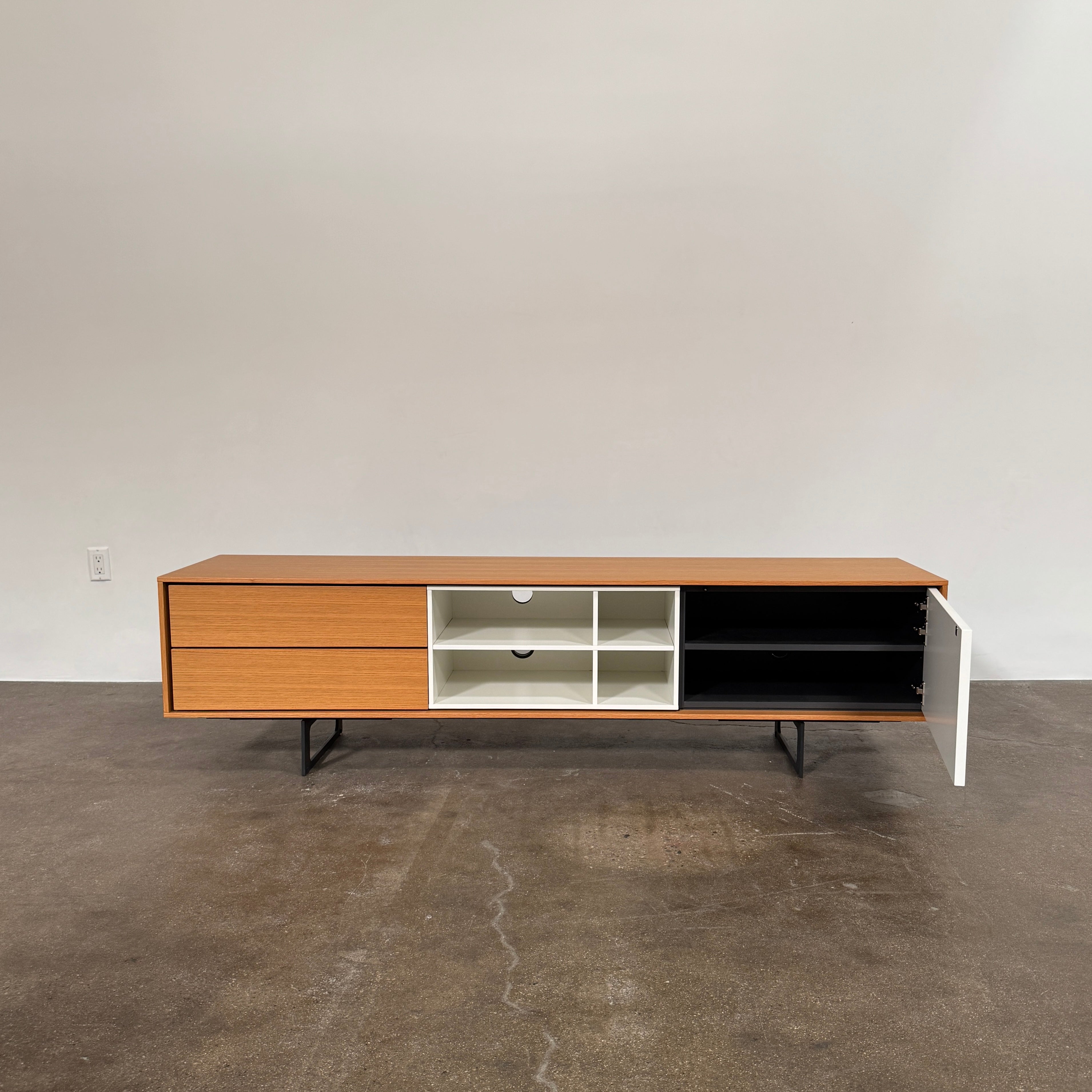 The Treku Aura Media Console by Treku features black metal legs, three left drawers, four open white center shelves, and a right white cabinet door—ideal for minimalist design and organizing your media equipment.