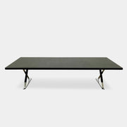The Maxalto Max Dining Table by Maxalto is a minimalist black rectangular table made from brushed black oak, featuring a flat top with modern X-shaped metal legs.