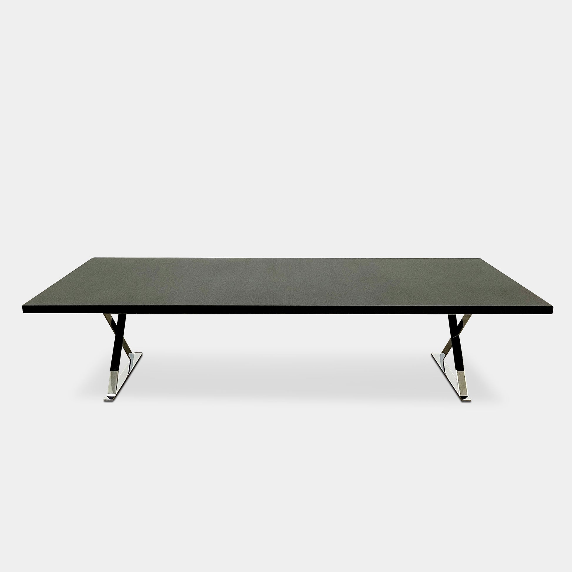 The Maxalto Max Dining Table by Maxalto is a minimalist black rectangular table made from brushed black oak, featuring a flat top with modern X-shaped metal legs.