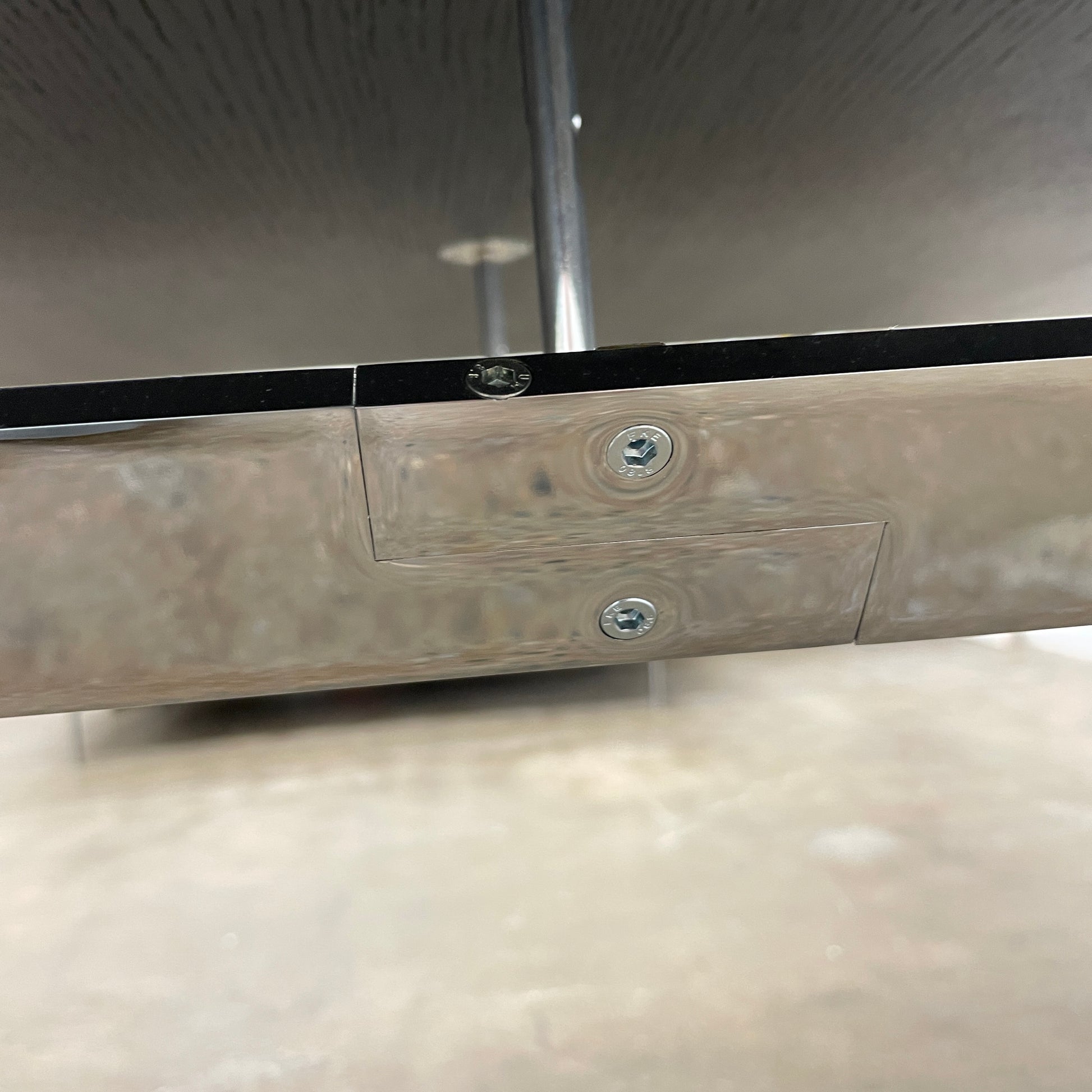 The Maxalto Max Dining Table by Maxalto is a minimalist black rectangular table made from brushed black oak, featuring a flat top with modern X-shaped metal legs.