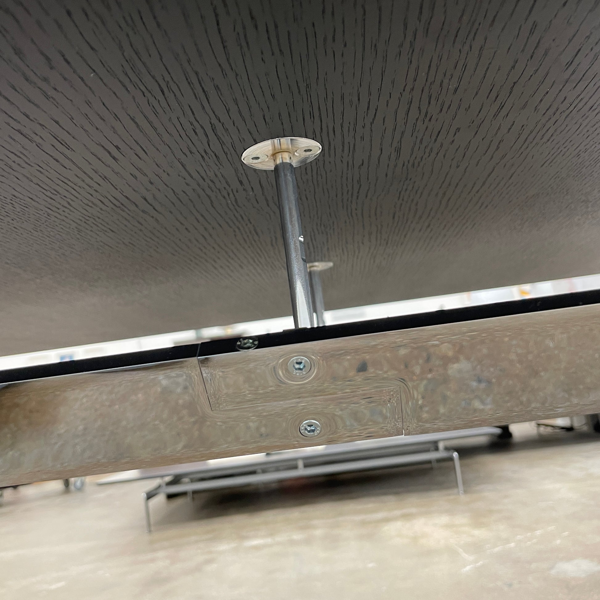 The Maxalto Max Dining Table by Maxalto is a minimalist black rectangular table made from brushed black oak, featuring a flat top with modern X-shaped metal legs.