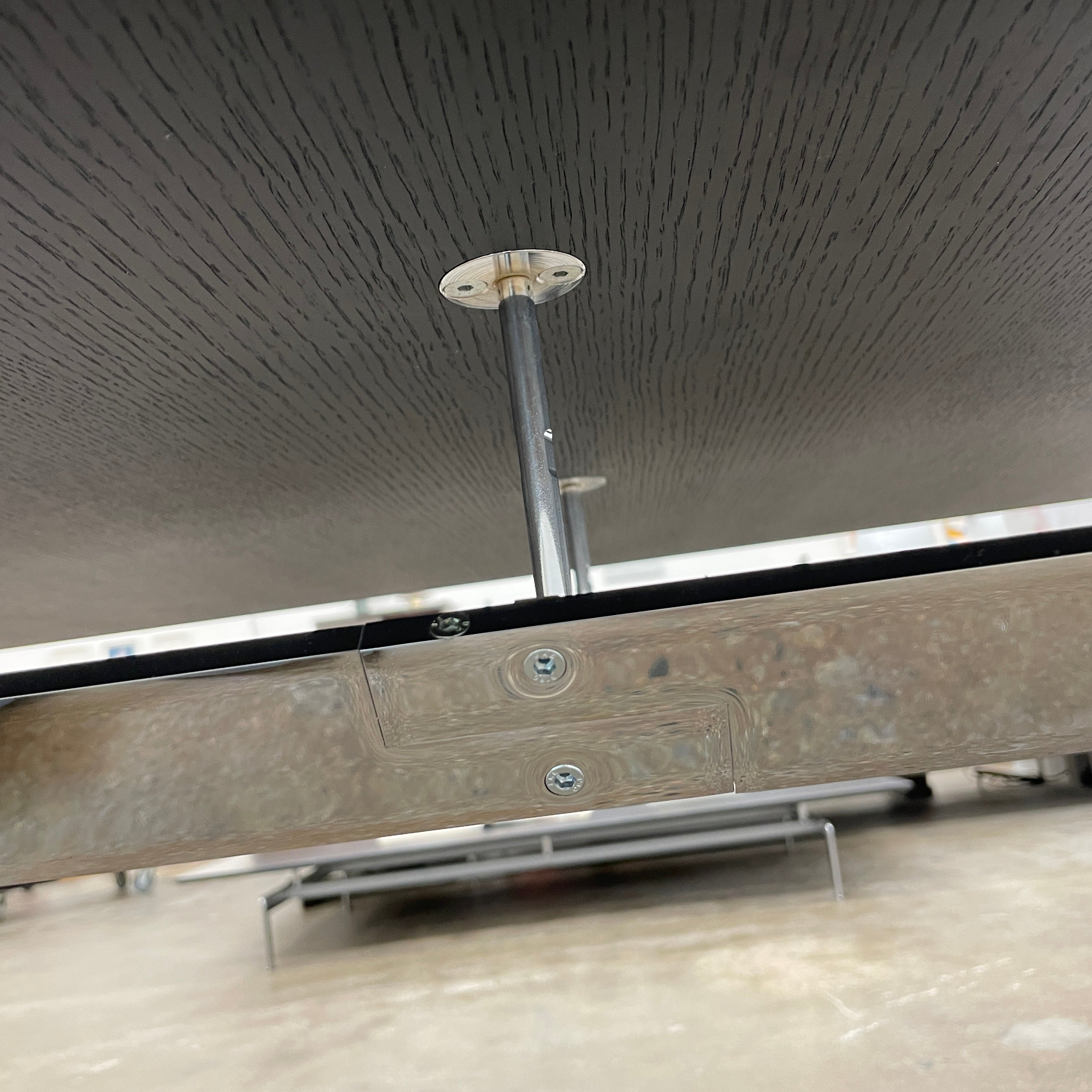 The Maxalto Max Dining Table by Maxalto is a minimalist black rectangular table made from brushed black oak, featuring a flat top with modern X-shaped metal legs.