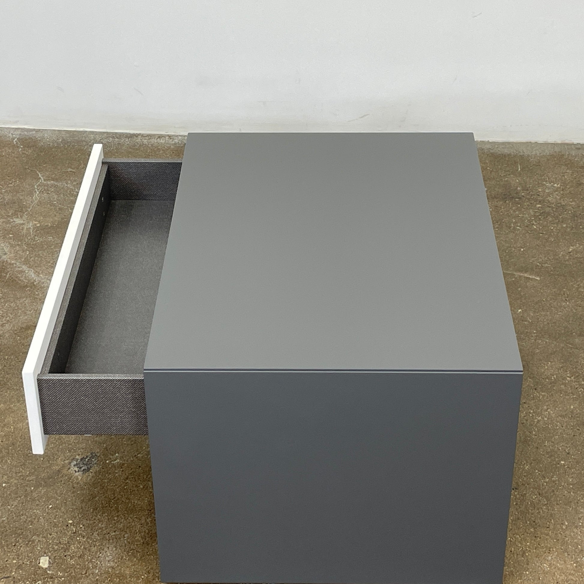 A rectangular gray and white lacquer box from B&B Italia, reminiscent of the Dado Night Table's minimalist design, features a glossy upper and matte lower section. This sleek piece serves as a stylish bedside companion, enhancing any modern space against a plain white background.