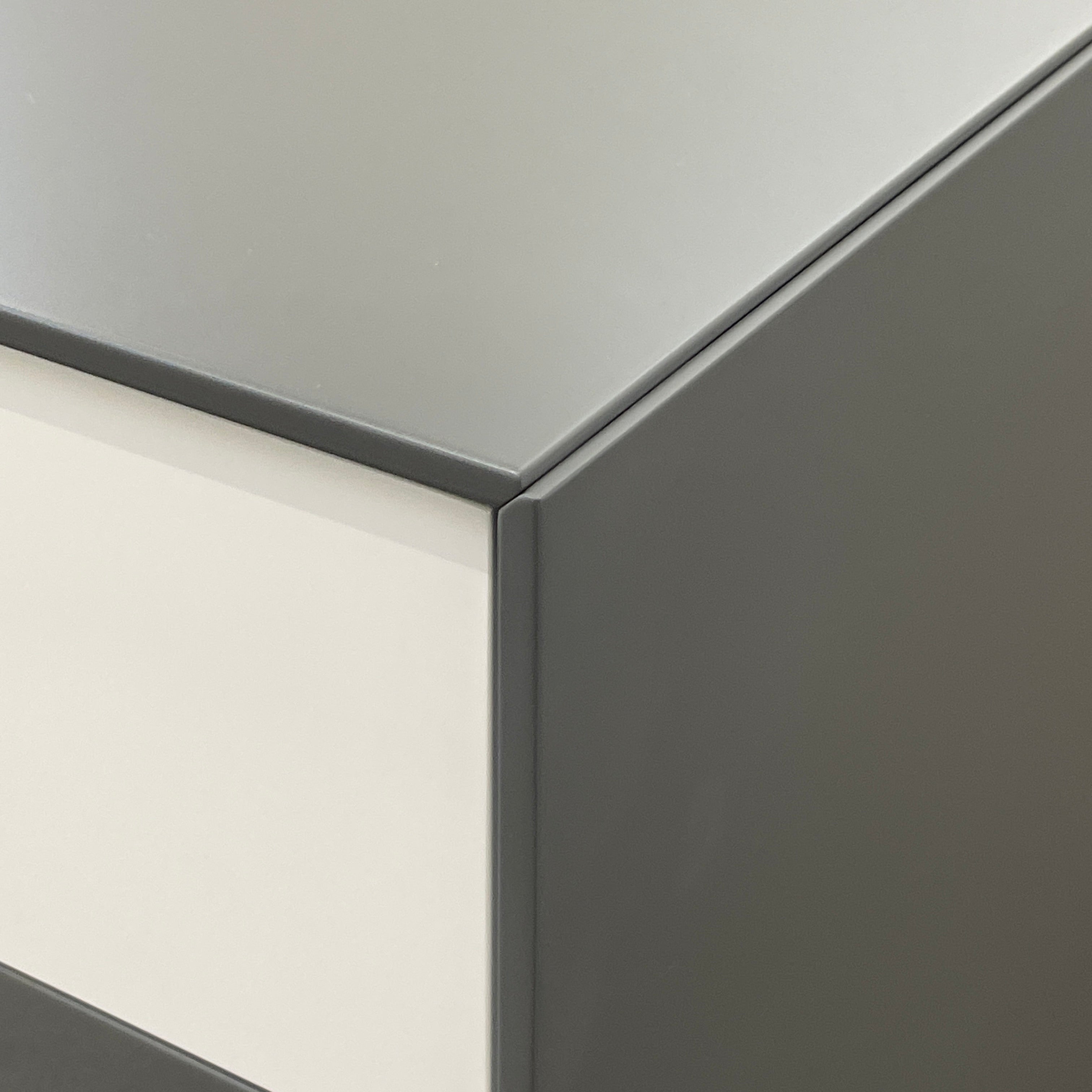 A rectangular gray and white lacquer box from B&B Italia, reminiscent of the Dado Night Table's minimalist design, features a glossy upper and matte lower section. This sleek piece serves as a stylish bedside companion, enhancing any modern space against a plain white background.