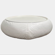 The B&B Italia Lady Fat Coffee Table by B&B Italia, a low, round table with a flat white top inspired by Patricia Urquiola’s design, sits on a plain brown floor against a light gray wall.