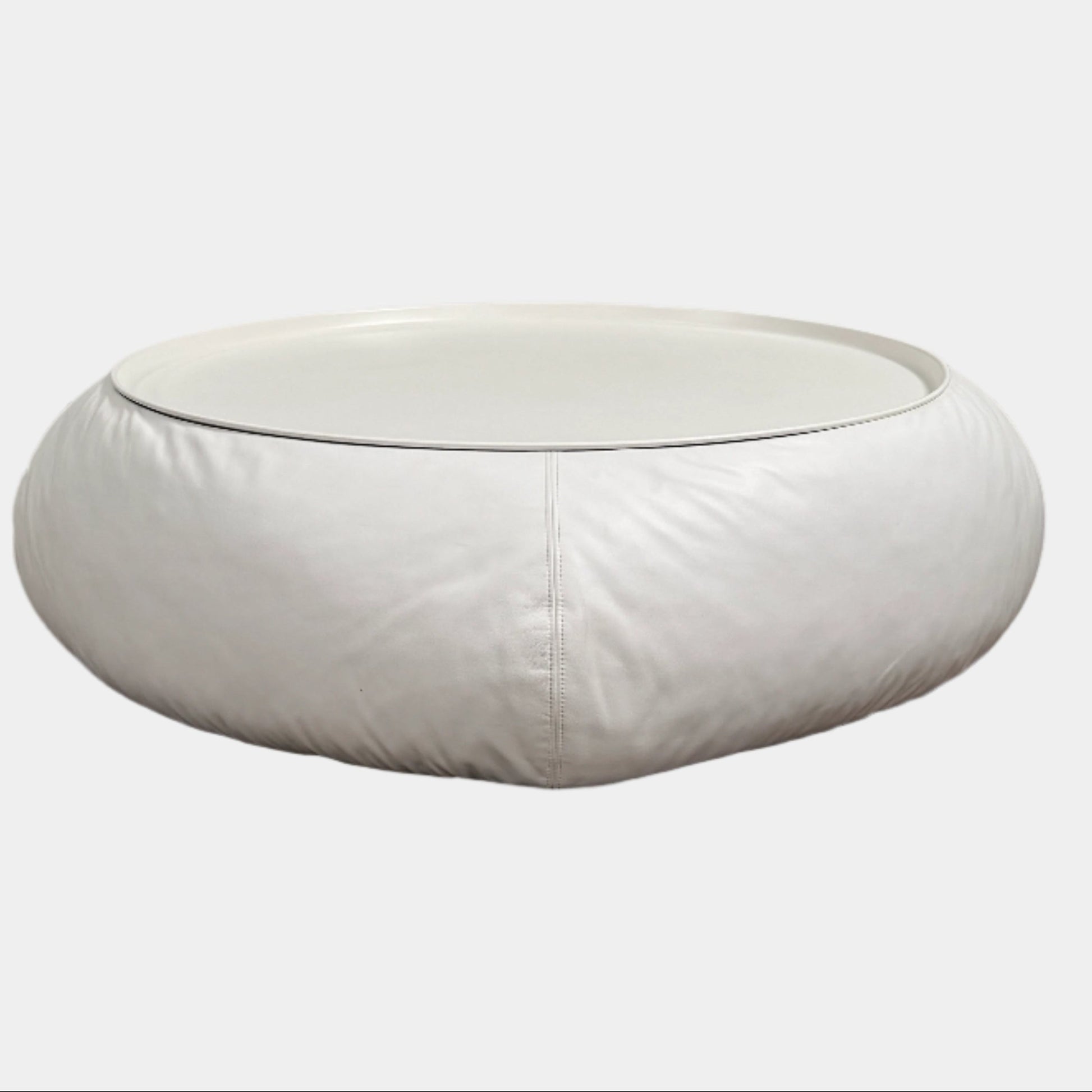 The B&B Italia Lady Fat Coffee Table by B&B Italia, a low, round table with a flat white top inspired by Patricia Urquiola’s design, sits on a plain brown floor against a light gray wall.