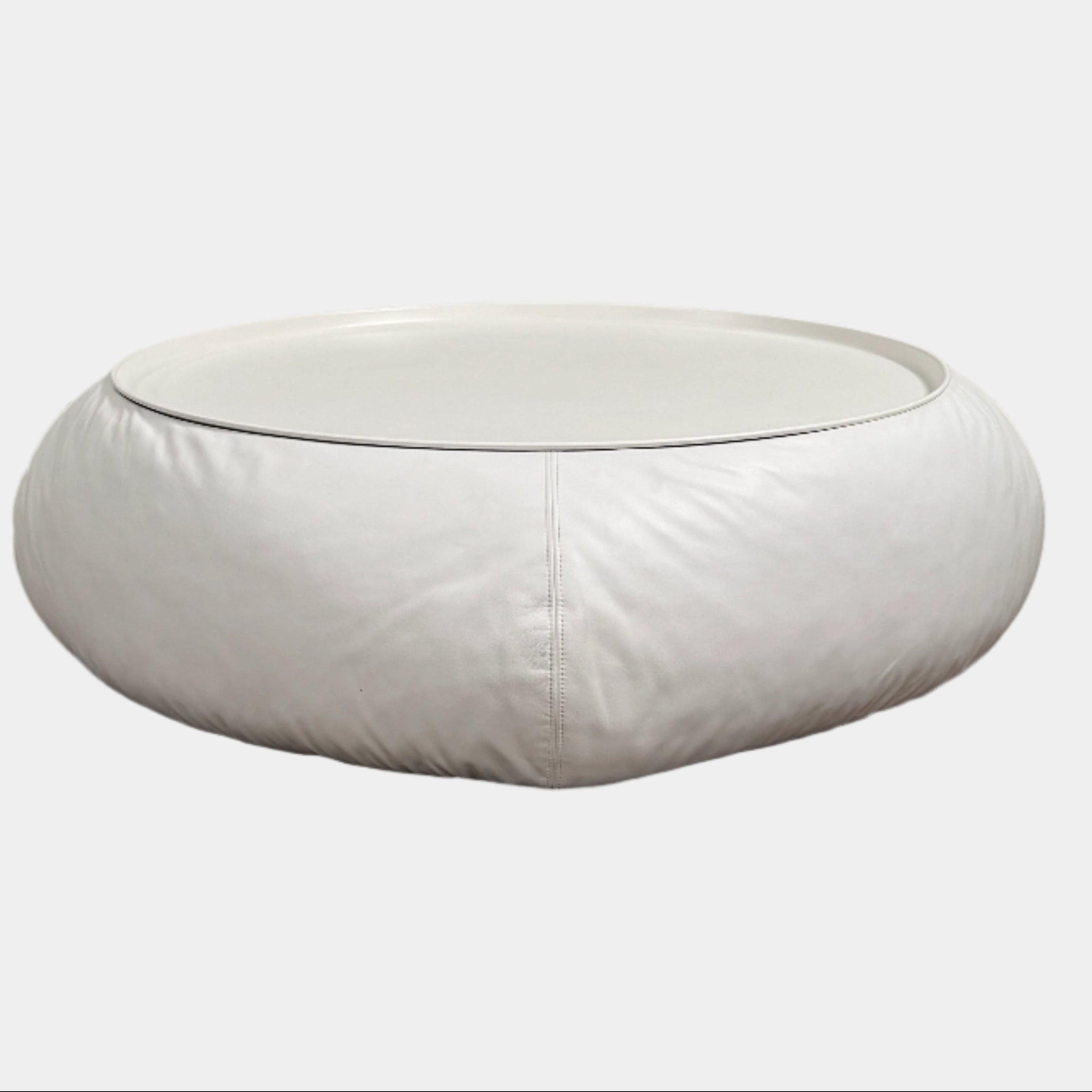 The B&B Italia Lady Fat Coffee Table by B&B Italia, a low, round table with a flat white top inspired by Patricia Urquiola’s design, sits on a plain brown floor against a light gray wall.