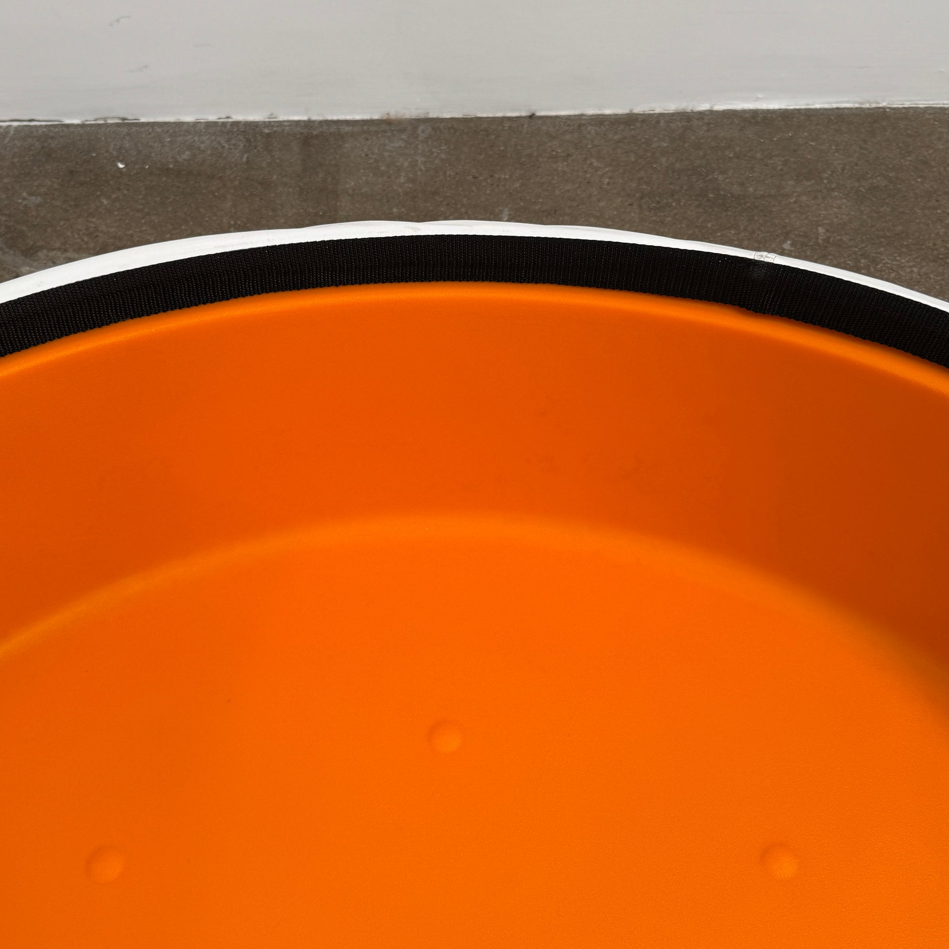 The B&B Italia Lady Fat Coffee Table by B&B Italia, a low, round table with a flat white top inspired by Patricia Urquiola’s design, sits on a plain brown floor against a light gray wall.