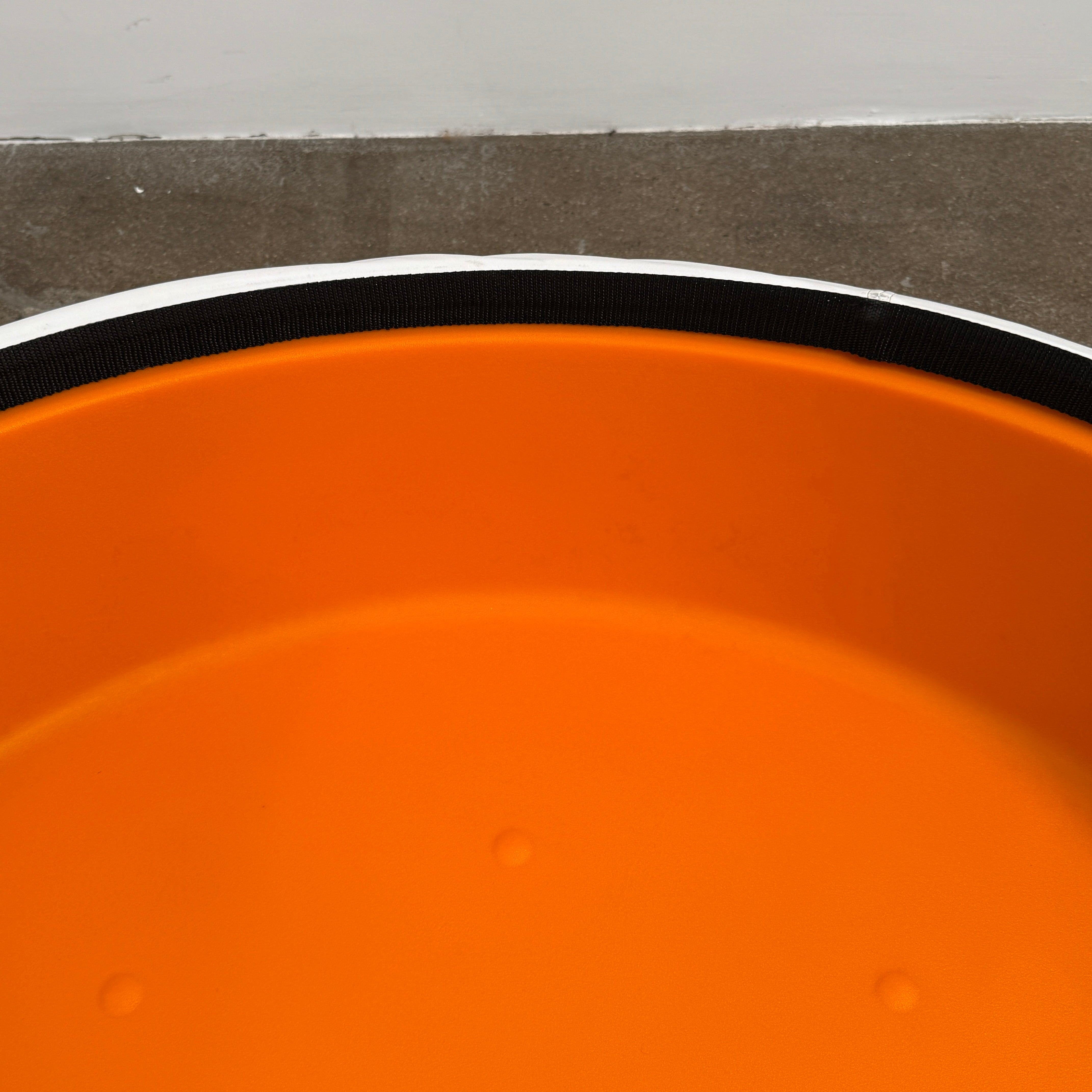 The B&B Italia Lady Fat Coffee Table by B&B Italia, a low, round table with a flat white top inspired by Patricia Urquiola’s design, sits on a plain brown floor against a light gray wall.