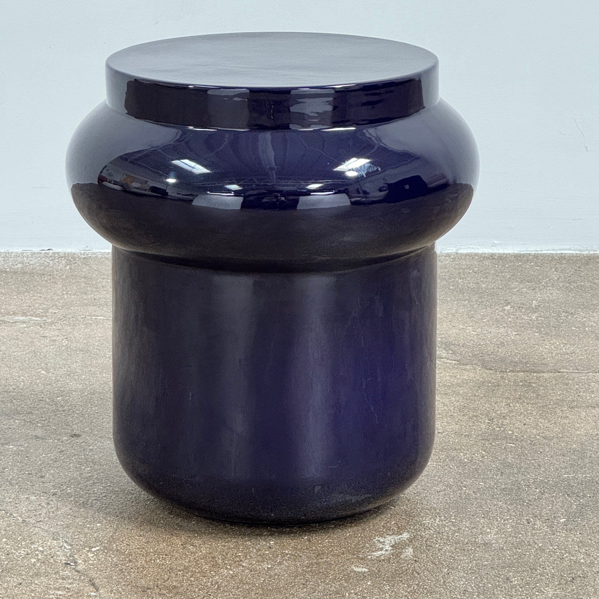 The Delcourt Collection Dot table by Delcourt Collection, designed by Charles Kalpakian, features a glossy ultramarine blue glaze and a dark blue cylindrical form with a wide, rounded top edge, set against a plain white background.
