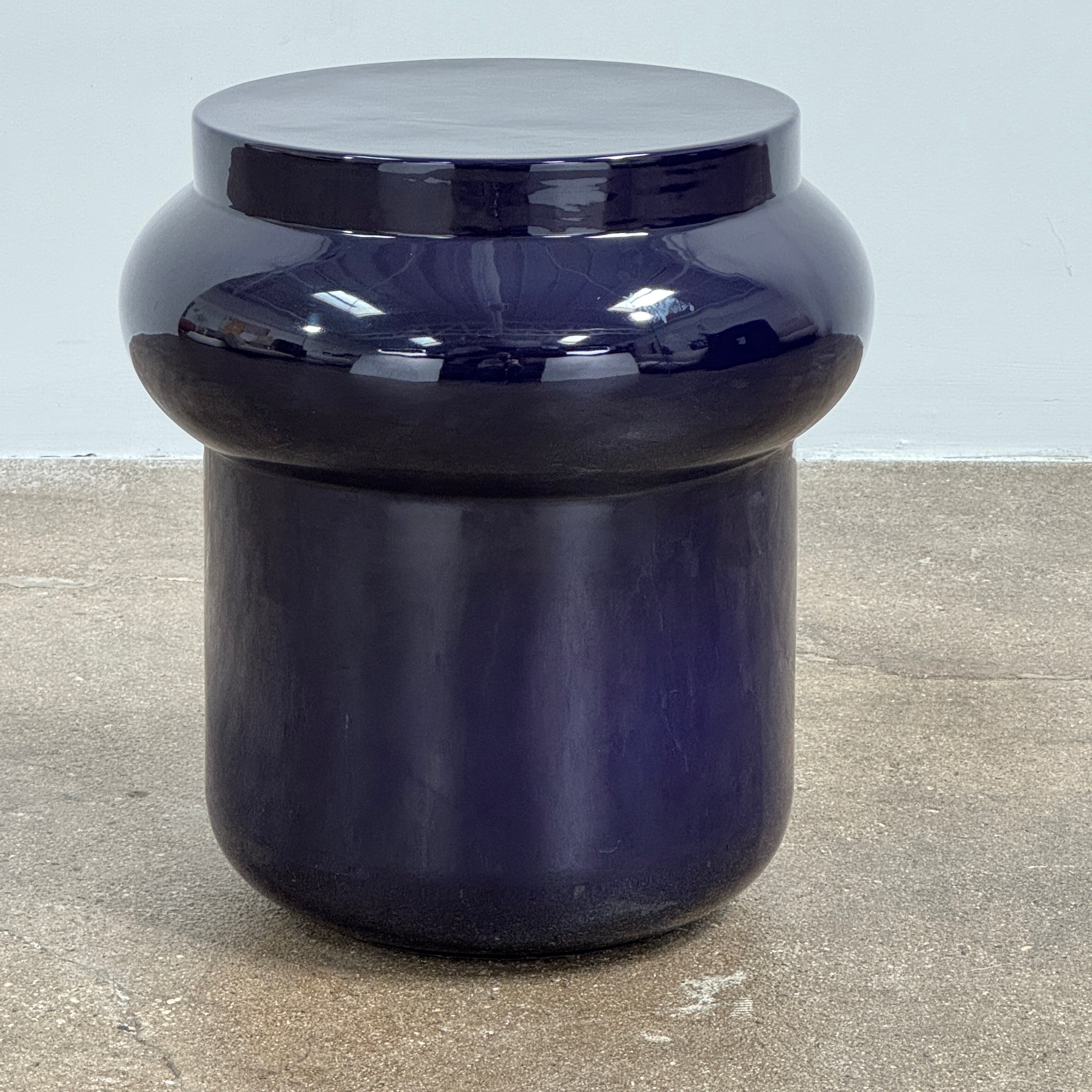 The Delcourt Collection Dot table by Delcourt Collection, designed by Charles Kalpakian, features a glossy ultramarine blue glaze and a dark blue cylindrical form with a wide, rounded top edge, set against a plain white background.