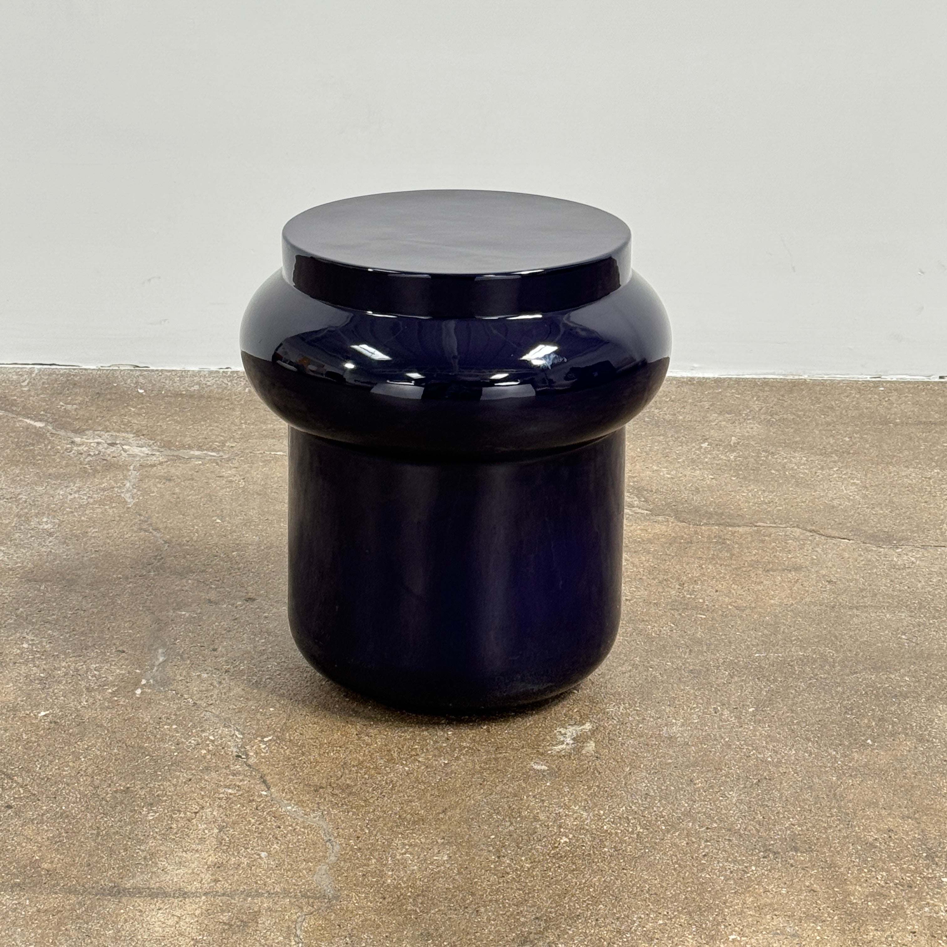 The Delcourt Collection Dot table by Delcourt Collection, designed by Charles Kalpakian, features a glossy ultramarine blue glaze and a dark blue cylindrical form with a wide, rounded top edge, set against a plain white background.