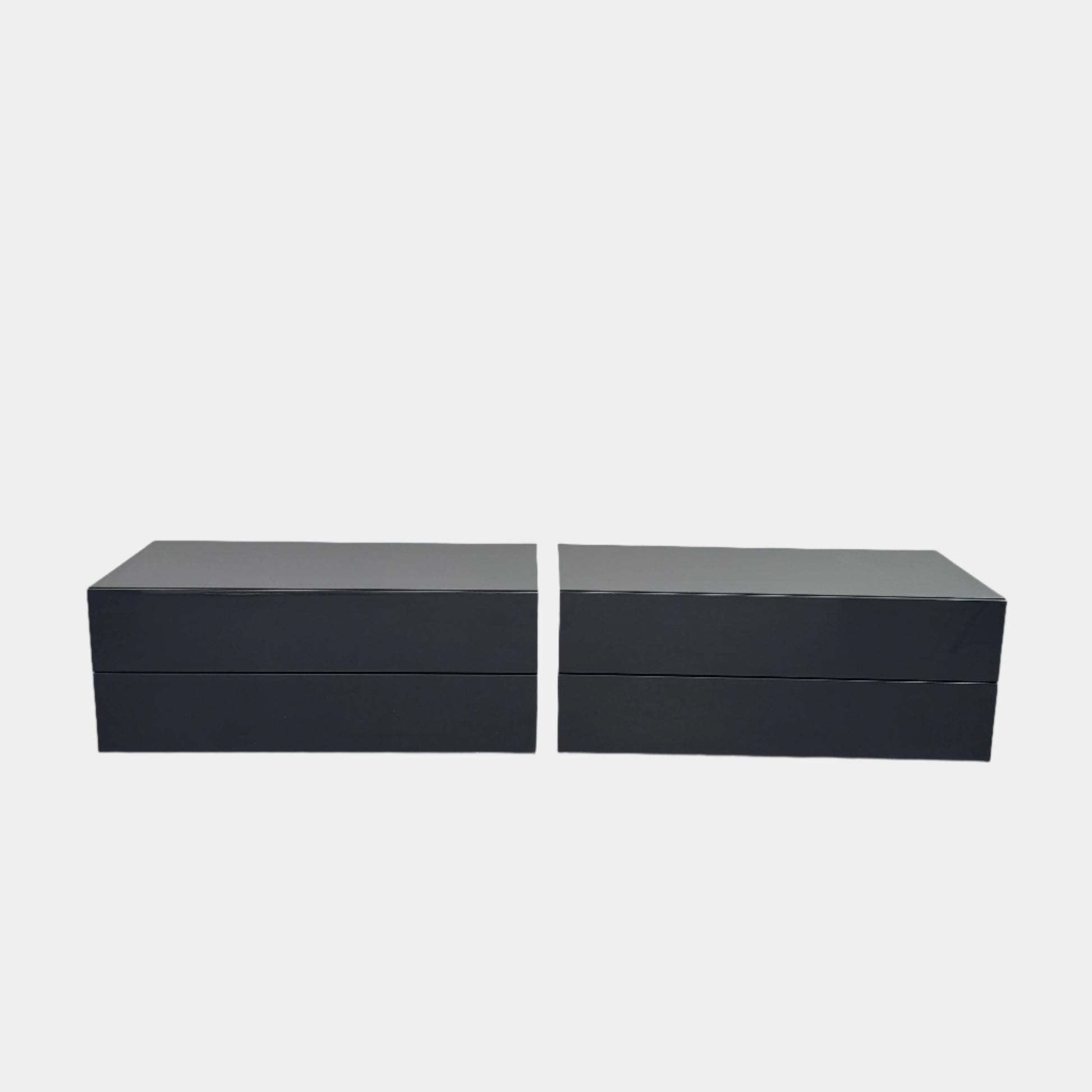 A pair of Poliform Dream Night Stands, each dark and rectangular with three drawers, stand side by side on a concrete floor against a plain white wall.