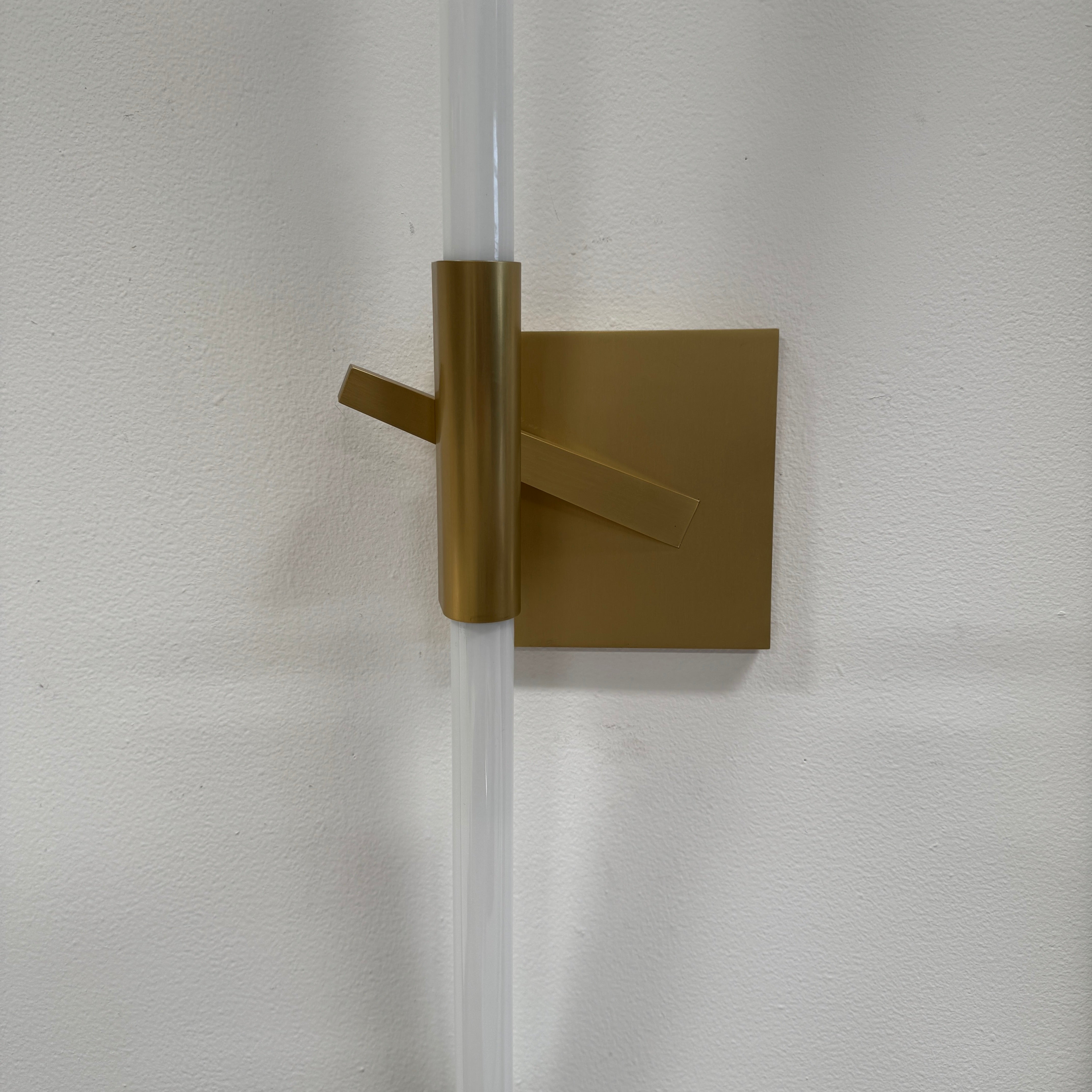 The Roll & Hill Agnes Wall Sconces (Set of 2) feature vertical cylindrical white fixtures on square brass bases with geometric and angled brass accents for a modern look.