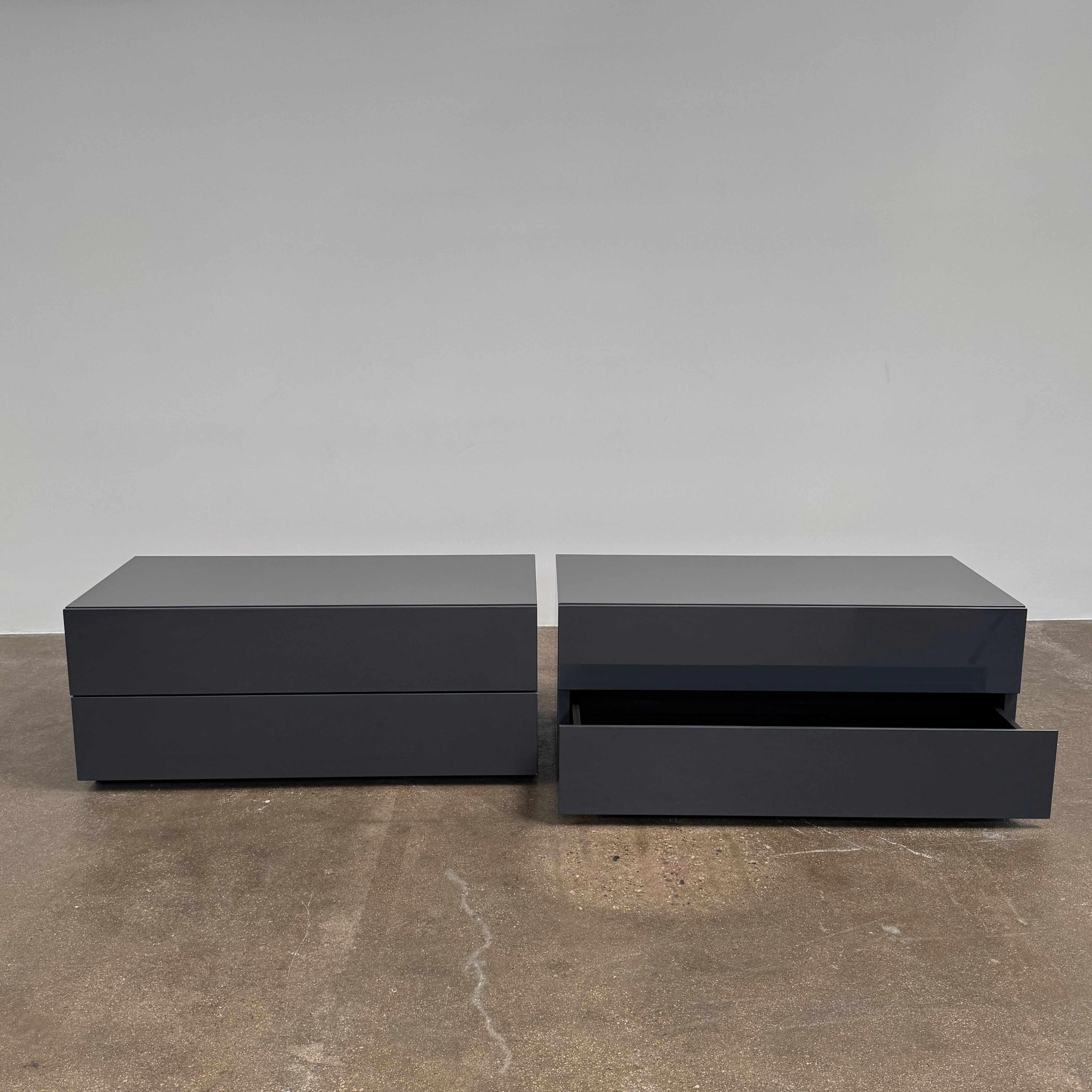 A pair of Poliform Dream Night Stands, each dark and rectangular with three drawers, stand side by side on a concrete floor against a plain white wall.
