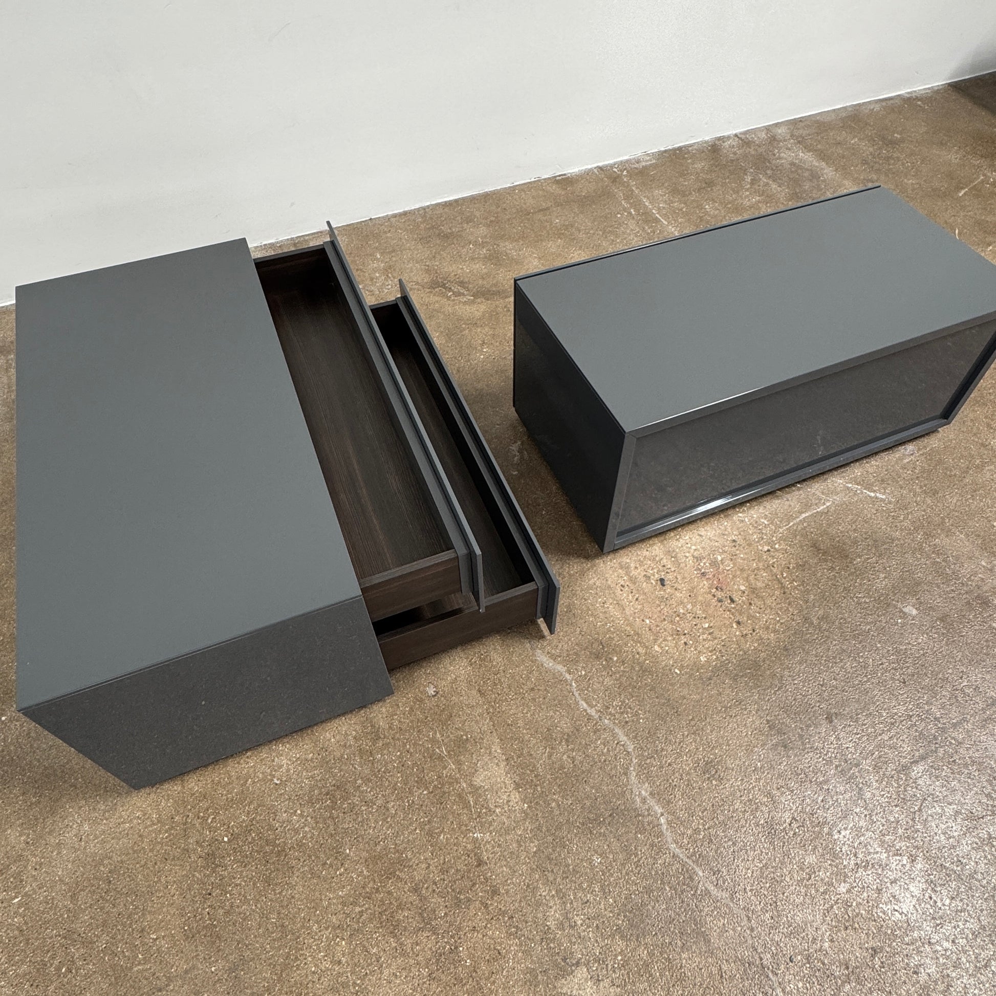A pair of Poliform Dream Night Stands, each dark and rectangular with three drawers, stand side by side on a concrete floor against a plain white wall.