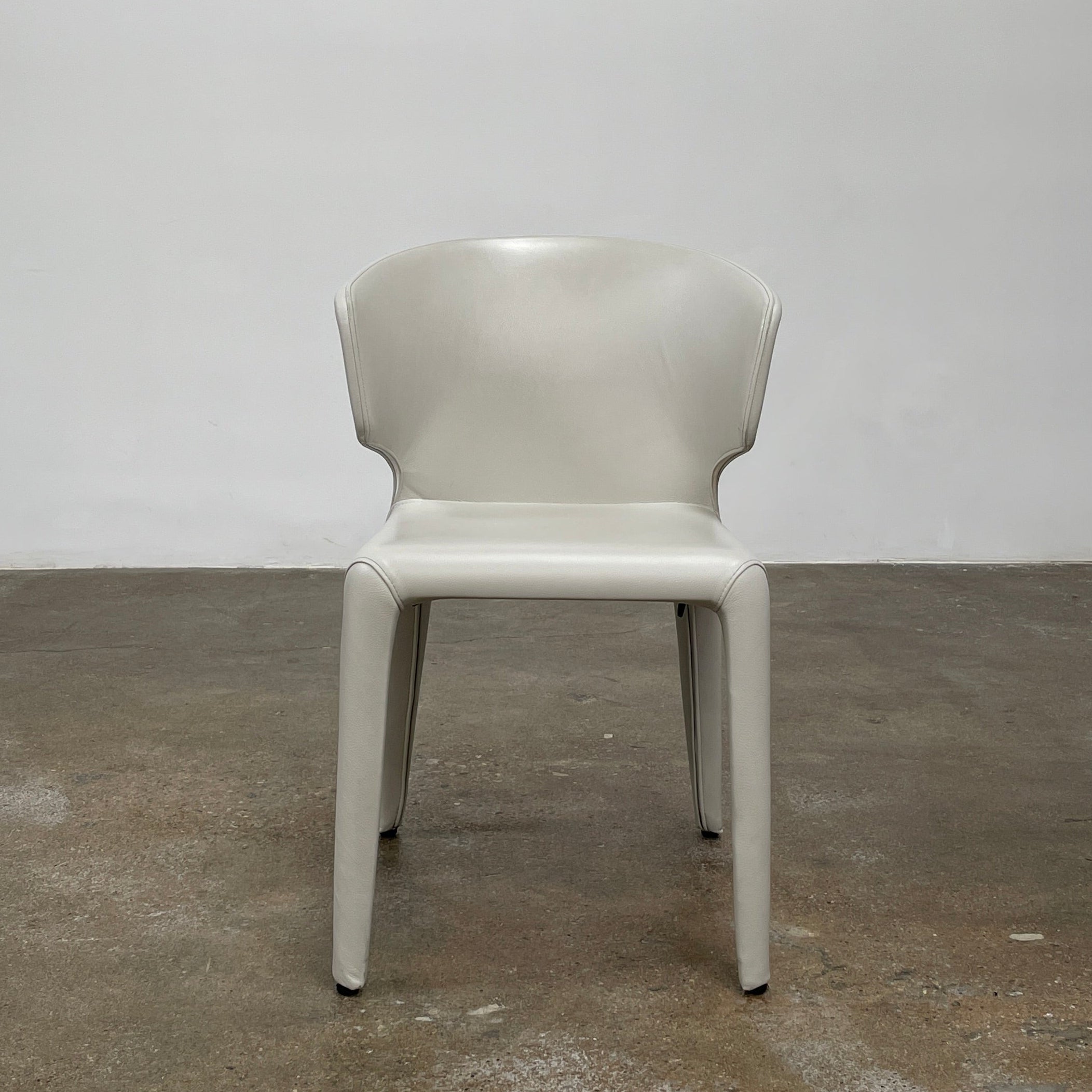 Six Cassina Hola 367 Dining Chairs, identical and upholstered in white leather, are elegantly arranged in two rows on a plain background.