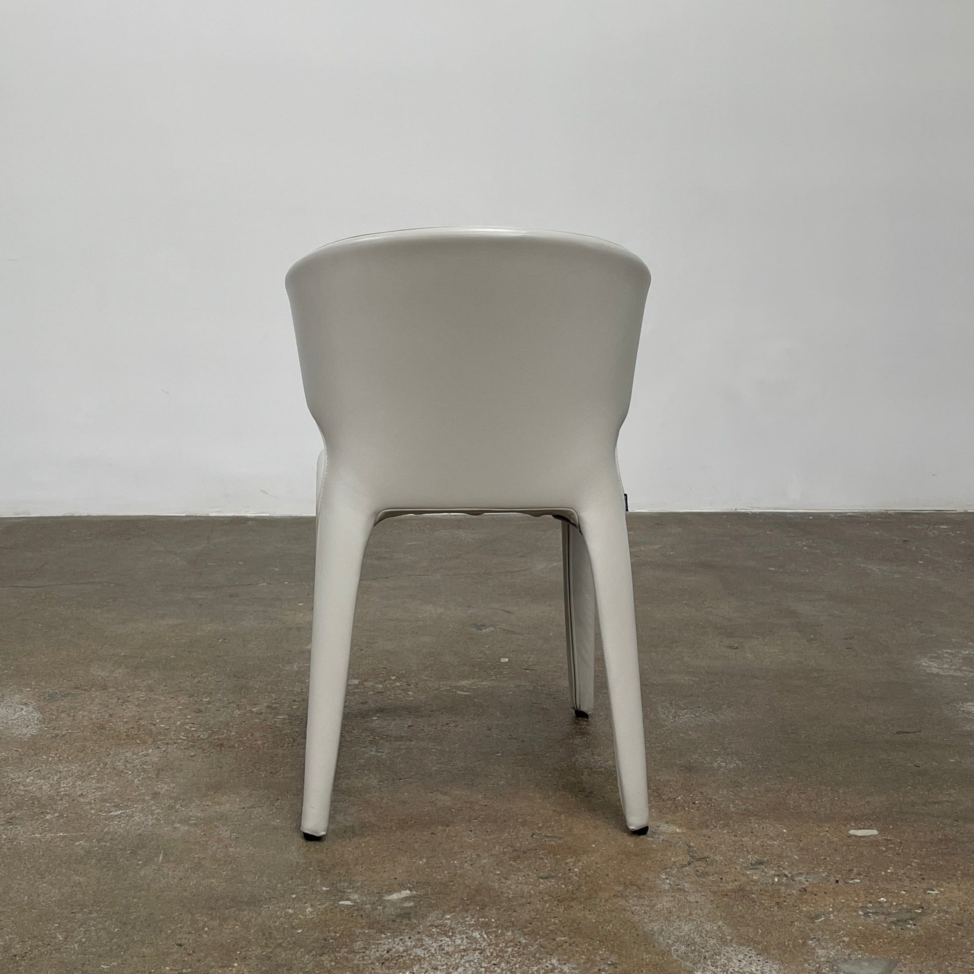 Six Cassina Hola 367 Dining Chairs, identical and upholstered in white leather, are elegantly arranged in two rows on a plain background.