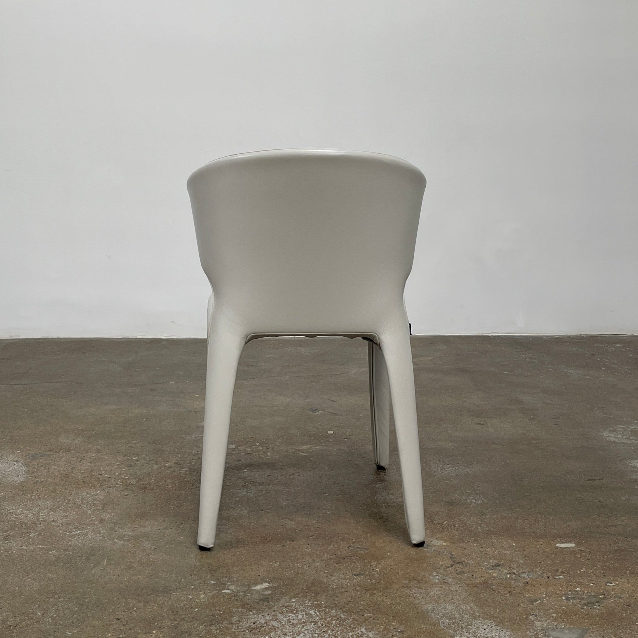 Six Cassina Hola 367 Dining Chairs, identical and upholstered in white leather, are elegantly arranged in two rows on a plain background.