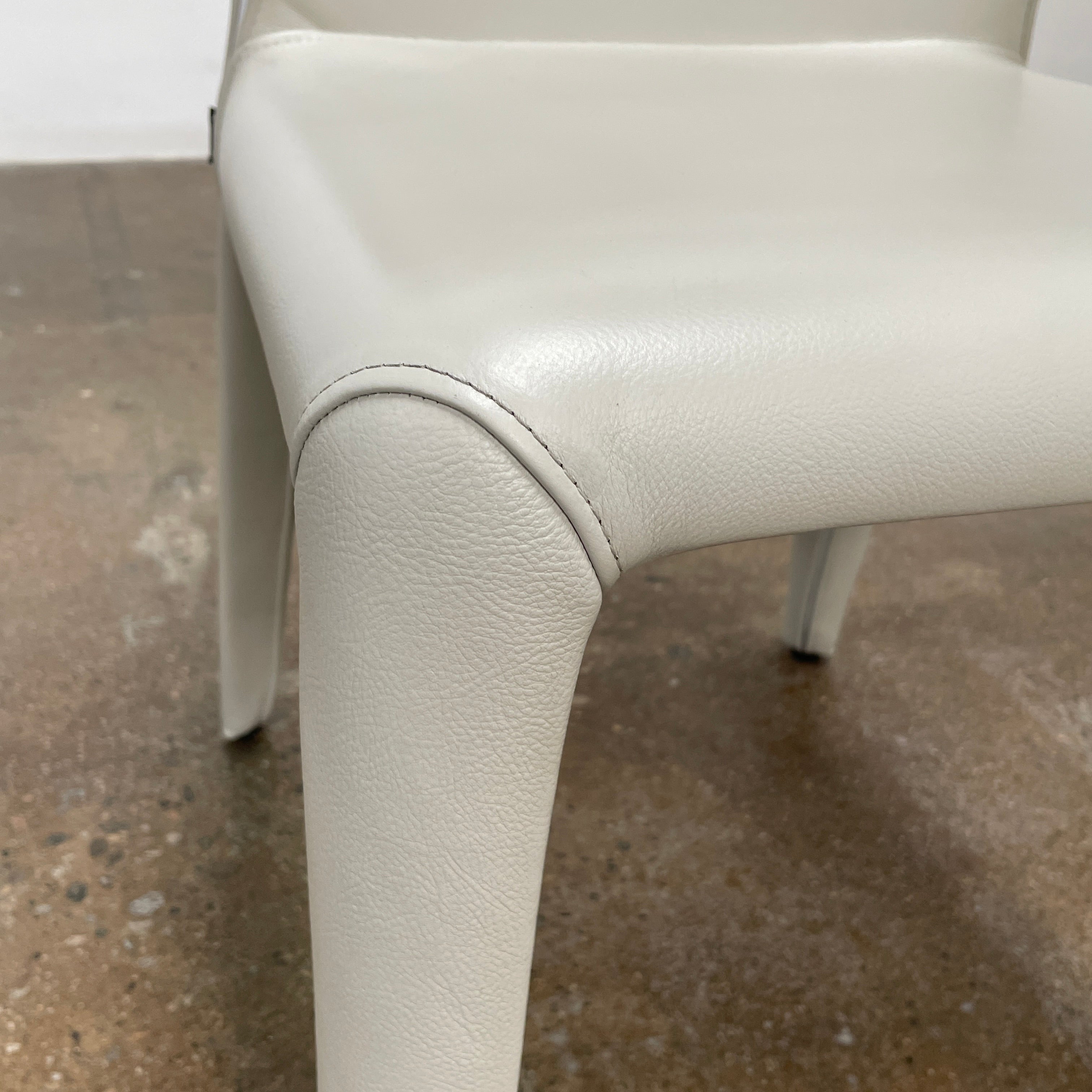 Six Cassina Hola 367 Dining Chairs, identical and upholstered in white leather, are elegantly arranged in two rows on a plain background.