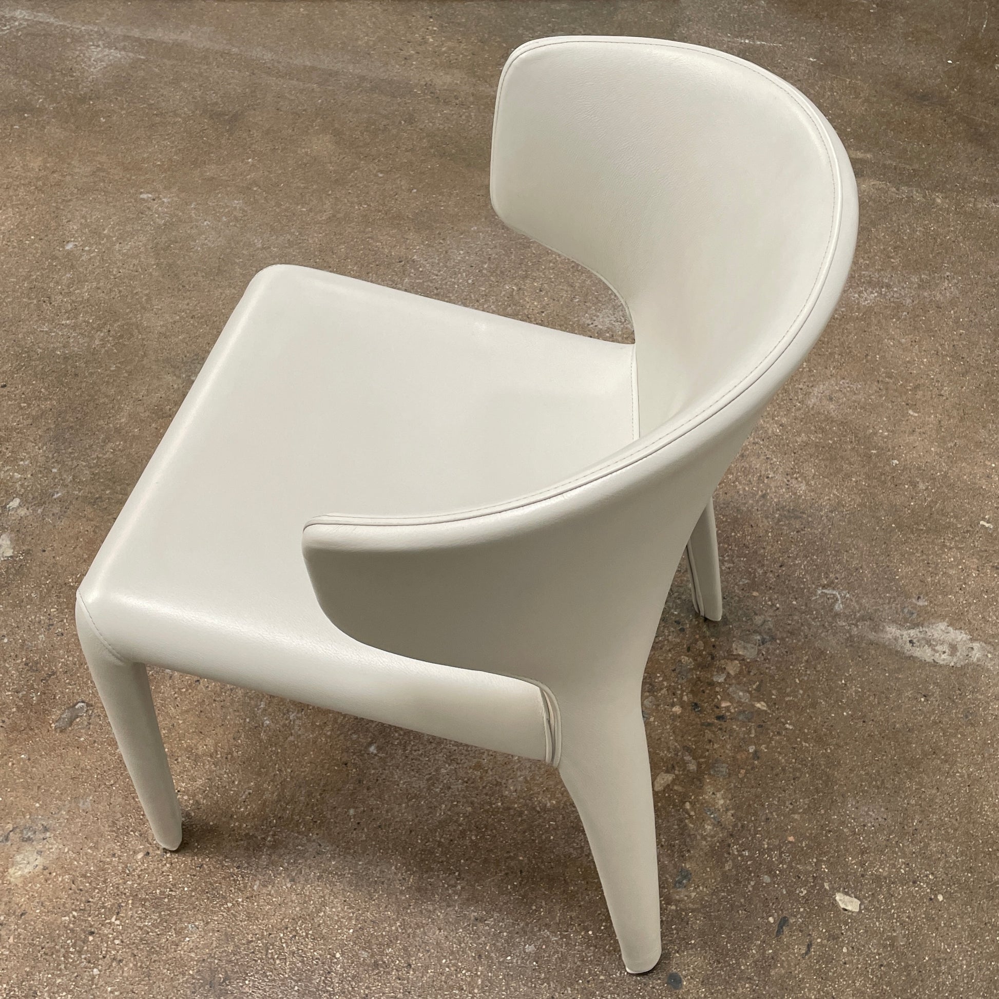 Six Cassina Hola 367 Dining Chairs, identical and upholstered in white leather, are elegantly arranged in two rows on a plain background.