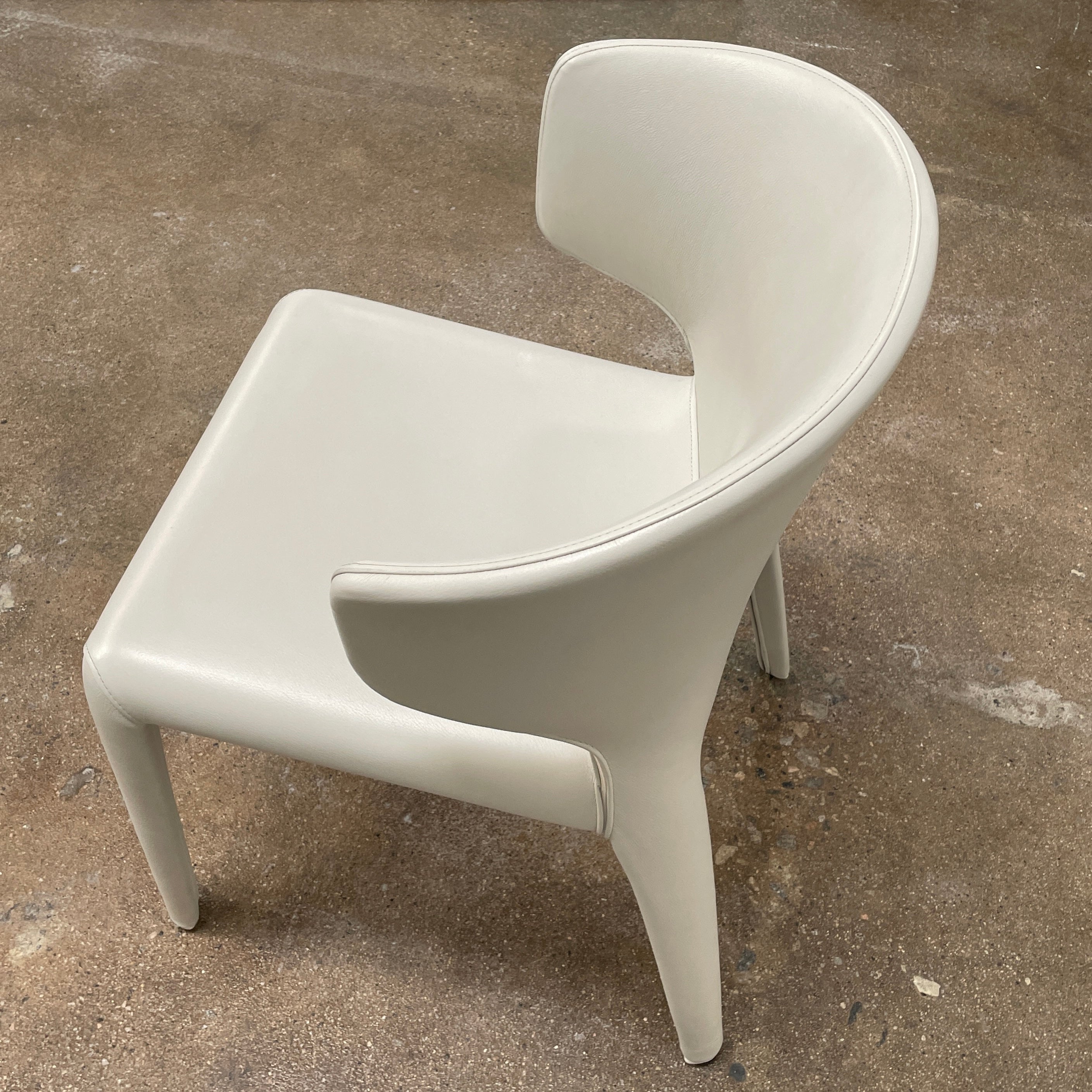 Six Cassina Hola 367 Dining Chairs, identical and upholstered in white leather, are elegantly arranged in two rows on a plain background.