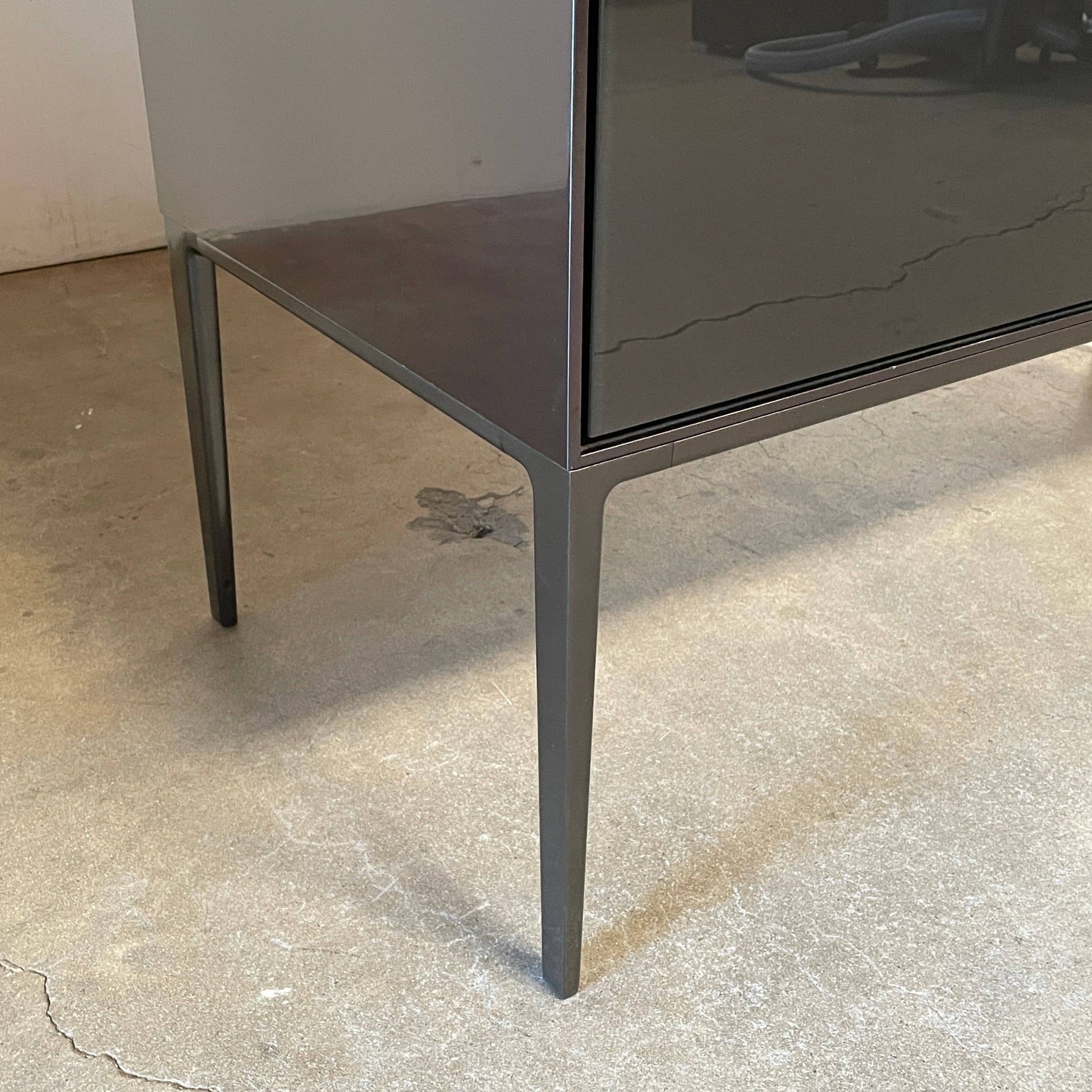 The B&B Italia Eucalipto Living Storage Unit is a sleek black metal cabinet with one drawer, two doors, and slim legs. It offers a minimalist and modern design, perfect for sophisticated bar storage.