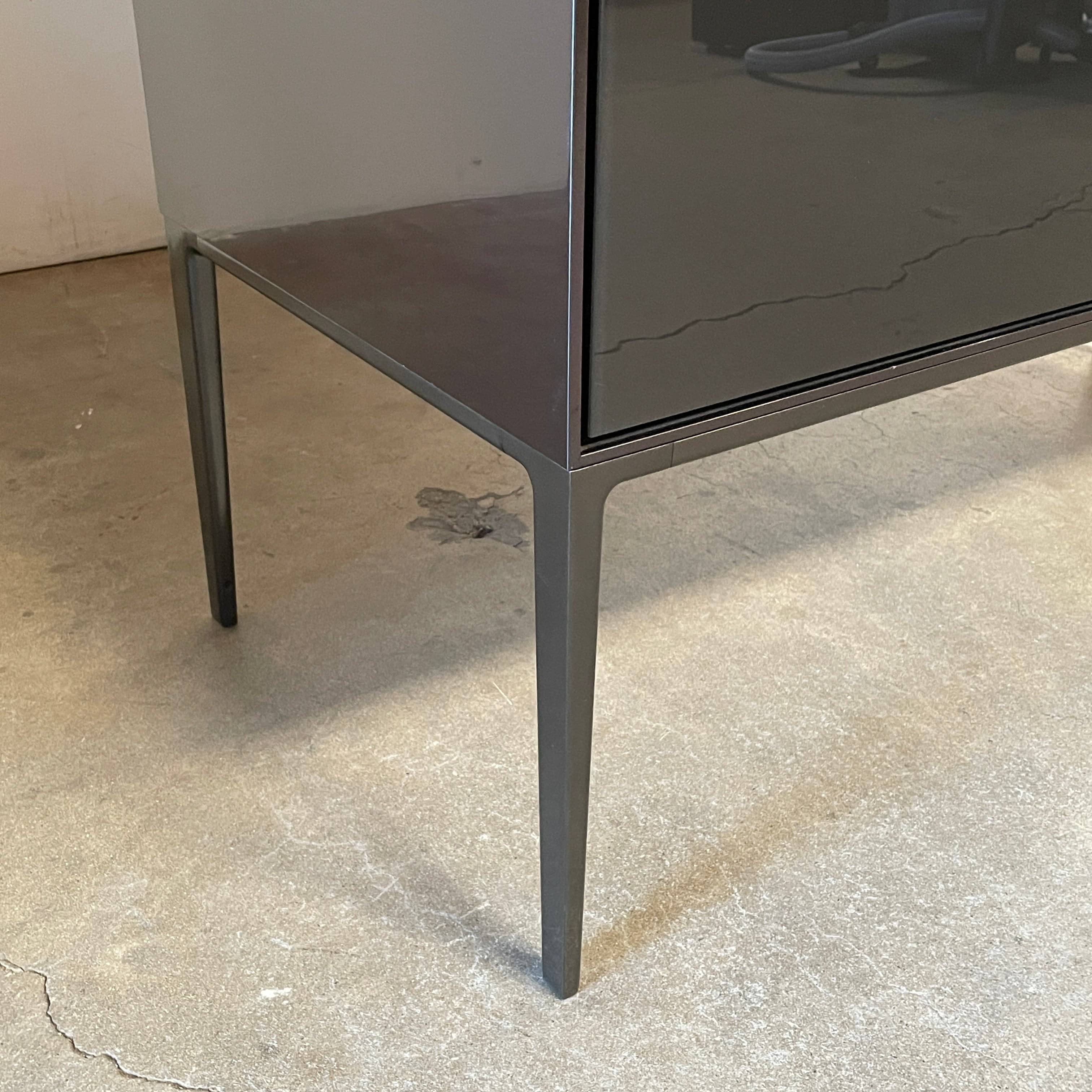 The B&B Italia Eucalipto Living Storage Unit is a sleek black metal cabinet with one drawer, two doors, and slim legs. It offers a minimalist and modern design, perfect for sophisticated bar storage.