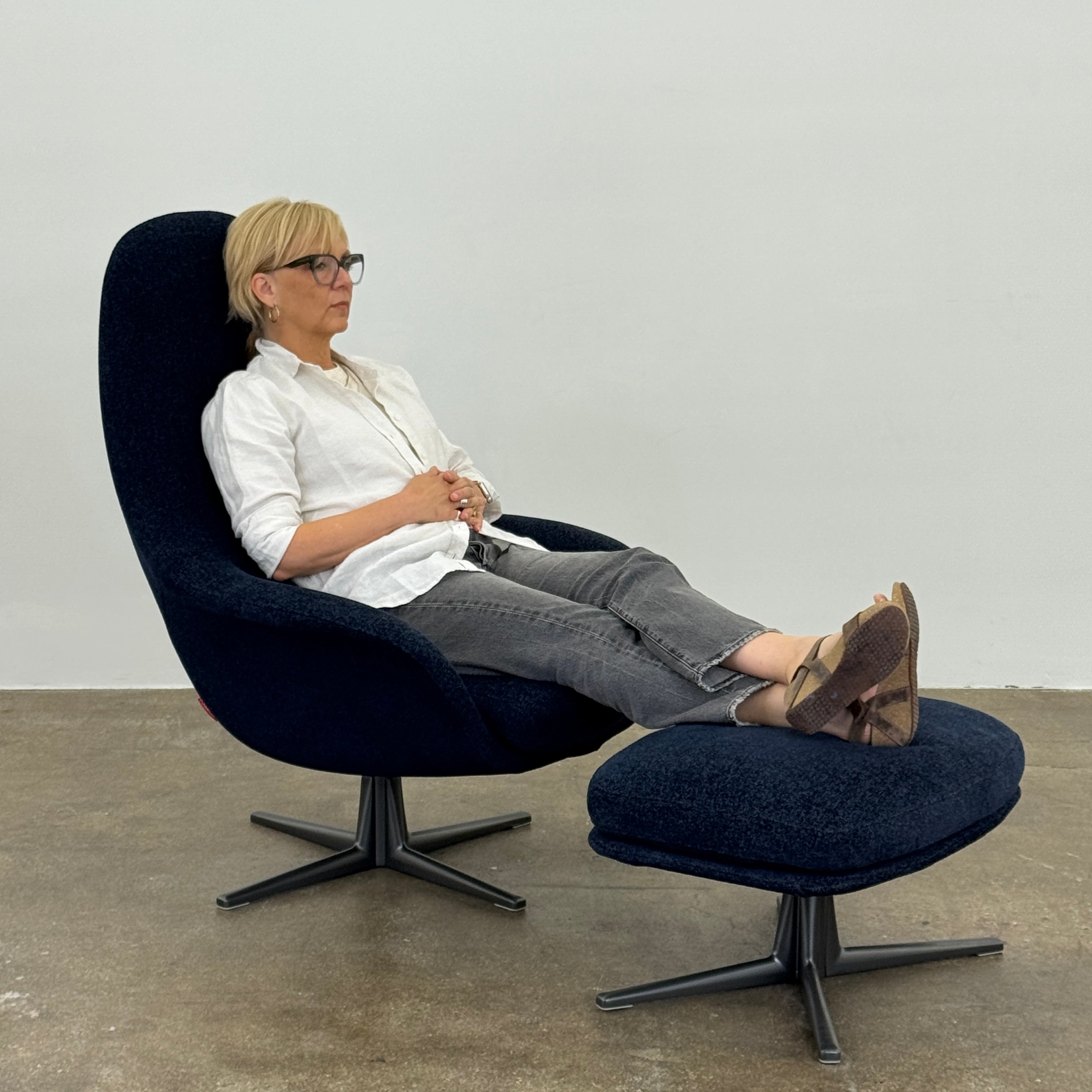 The Flexform Marlon Swivel Armchair and Ottoman, available with two covers, feature ergonomic design and black metal bases from Flexform, shown here in a modern gray finish against a plain white background.