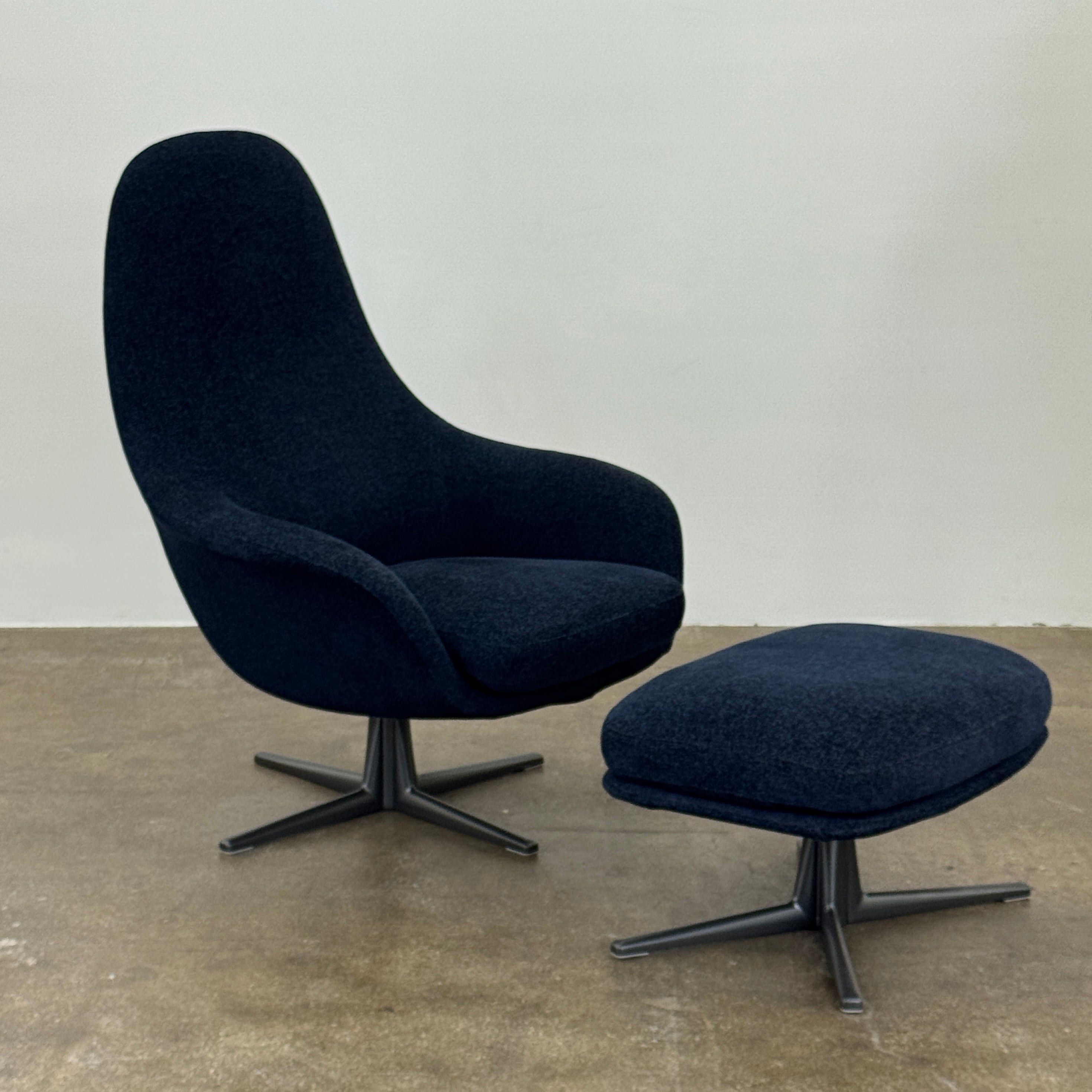 The Flexform Marlon Swivel Armchair and Ottoman, available with two covers, feature ergonomic design and black metal bases from Flexform, shown here in a modern gray finish against a plain white background.