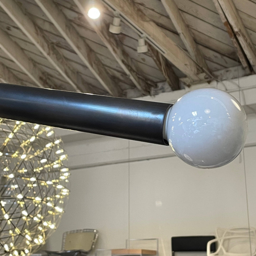 A Large Apparatus Studio Arrow Ceiling Light, by Apparatus Studio, hanging from a white ceiling.