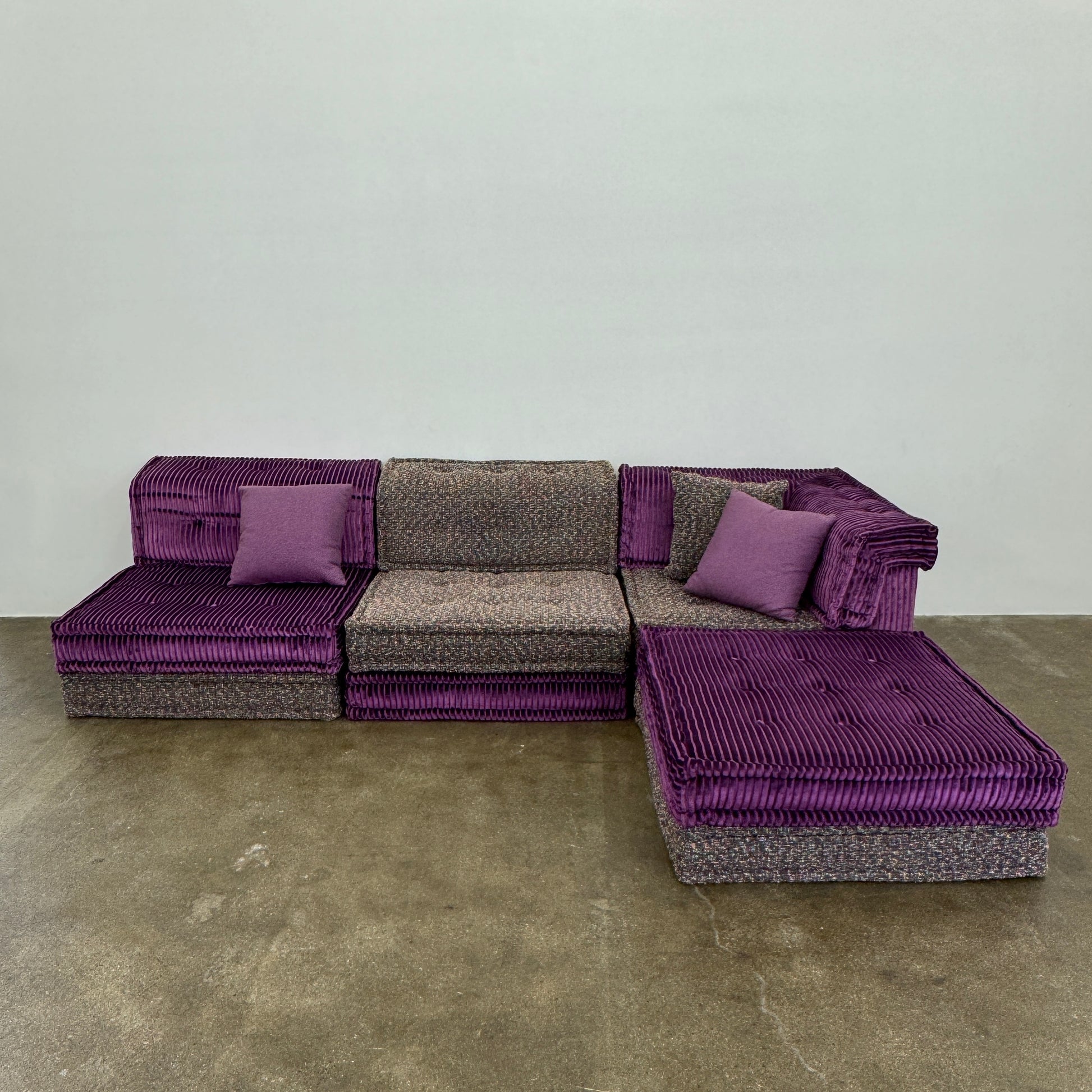 The Roche Bobois Mah Jong Sectional - Back with Mechanism by Roche Bobois features a modern modular design, purple and gray corduroy upholstery, and includes two purple throw pillows, inspired by the iconic Mah Jong sofa.