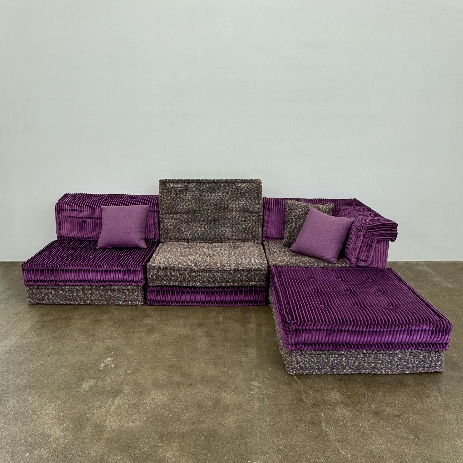 The Roche Bobois Mah Jong Sectional - Back with Mechanism by Roche Bobois features a modern modular design, purple and gray corduroy upholstery, and includes two purple throw pillows, inspired by the iconic Mah Jong sofa.