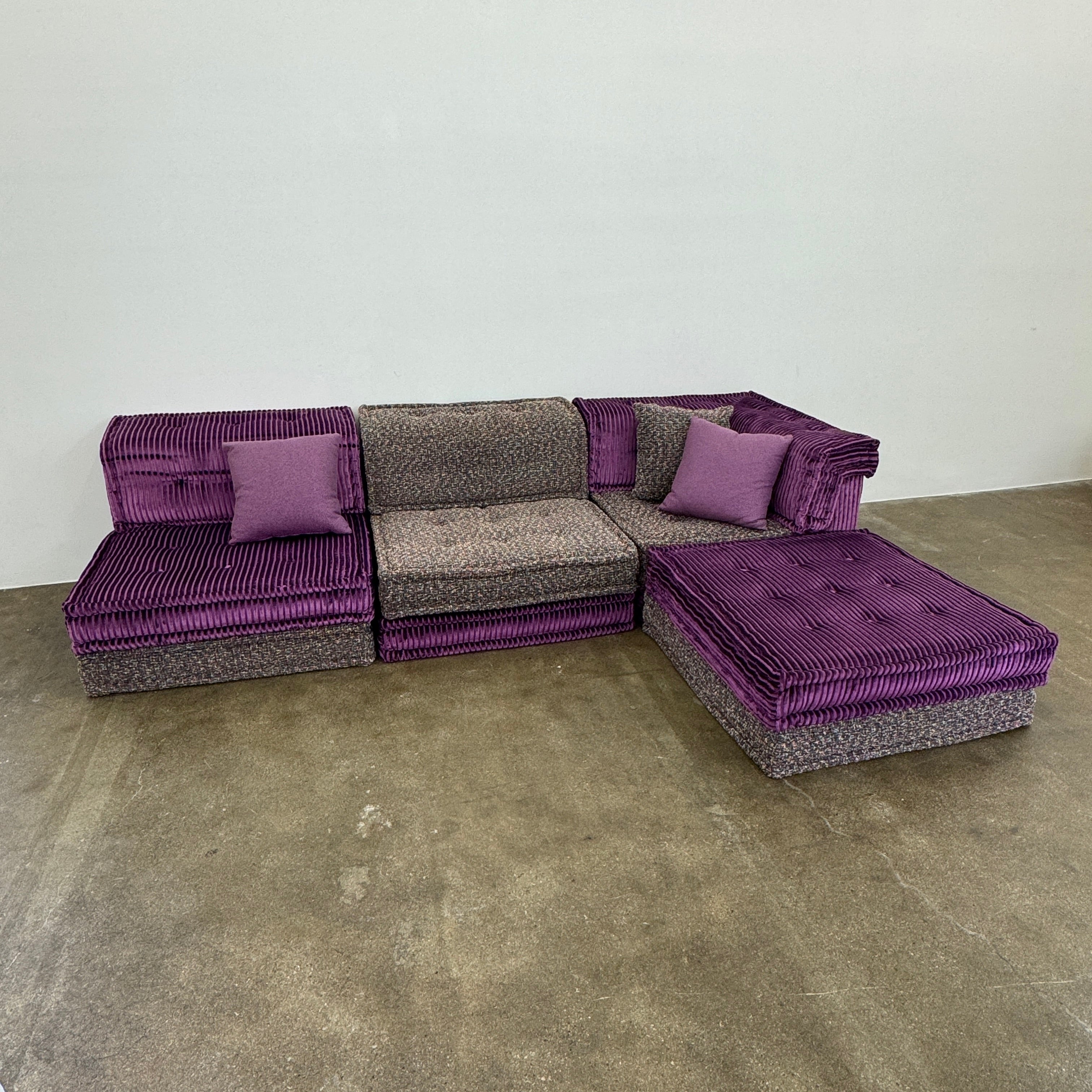 The Roche Bobois Mah Jong Sectional - Back with Mechanism by Roche Bobois features a modern modular design, purple and gray corduroy upholstery, and includes two purple throw pillows, inspired by the iconic Mah Jong sofa.