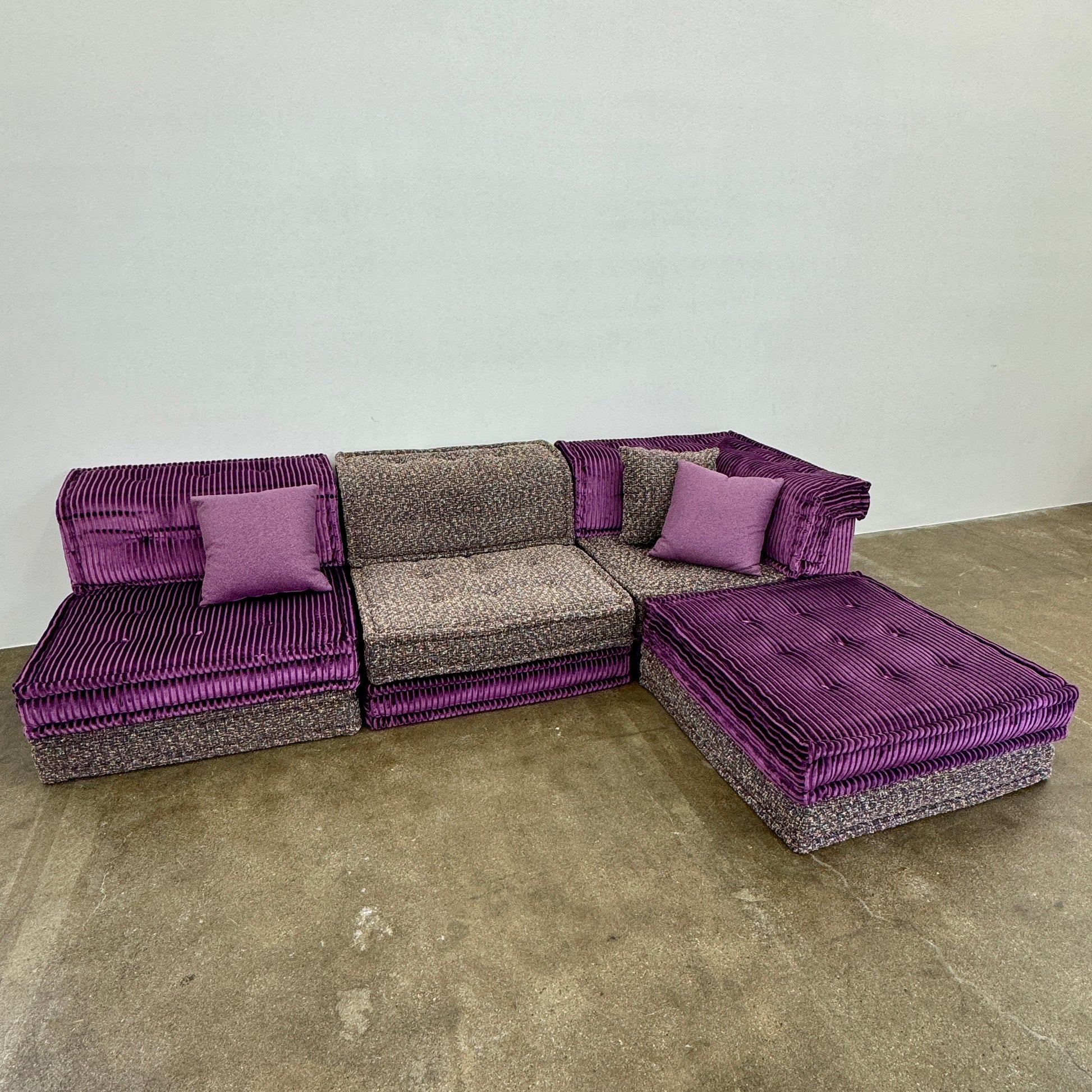 The Roche Bobois Mah Jong Sectional - Back with Mechanism by Roche Bobois features a modern modular design, purple and gray corduroy upholstery, and includes two purple throw pillows, inspired by the iconic Mah Jong sofa.