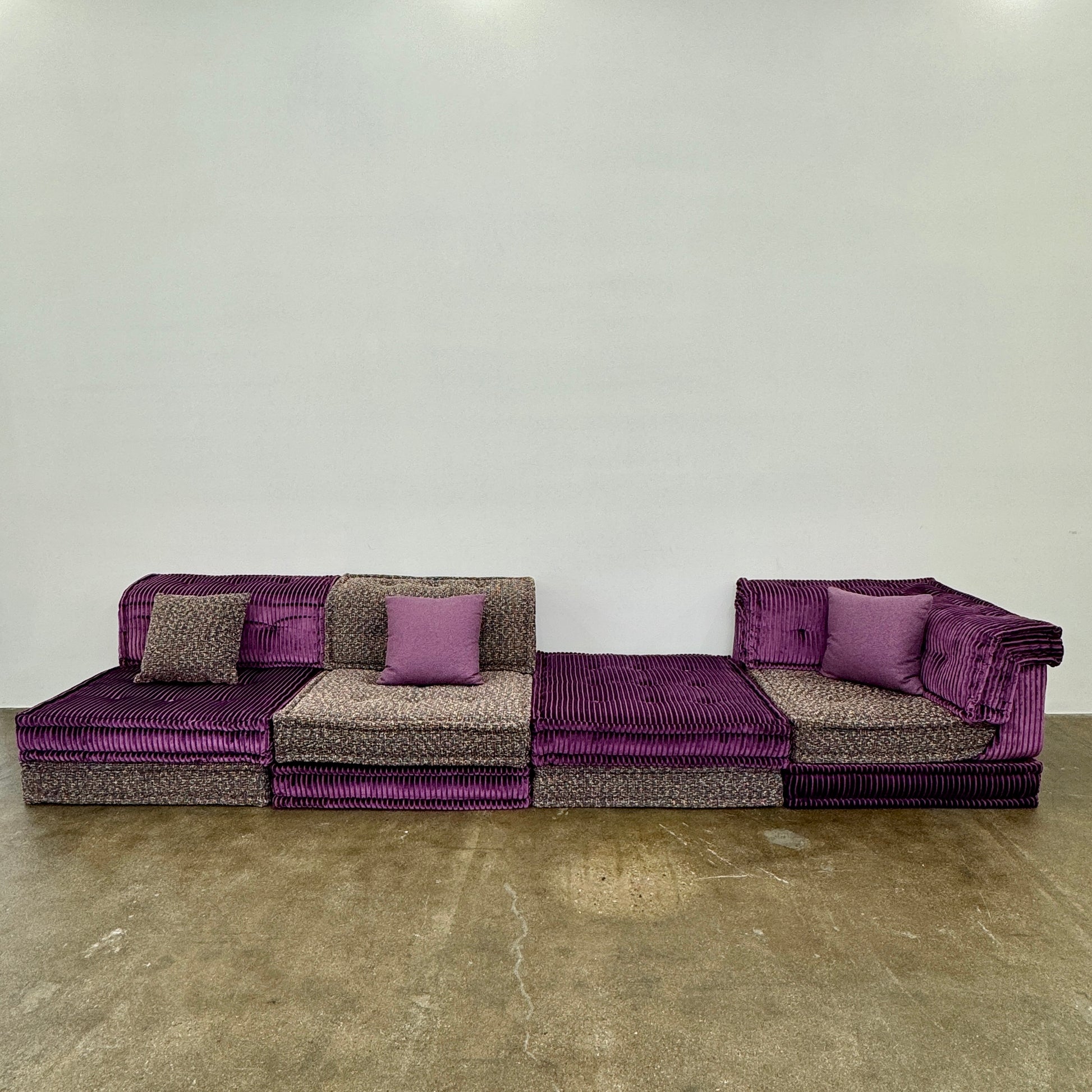 The Roche Bobois Mah Jong Sectional - Back with Mechanism by Roche Bobois features a modern modular design, purple and gray corduroy upholstery, and includes two purple throw pillows, inspired by the iconic Mah Jong sofa.